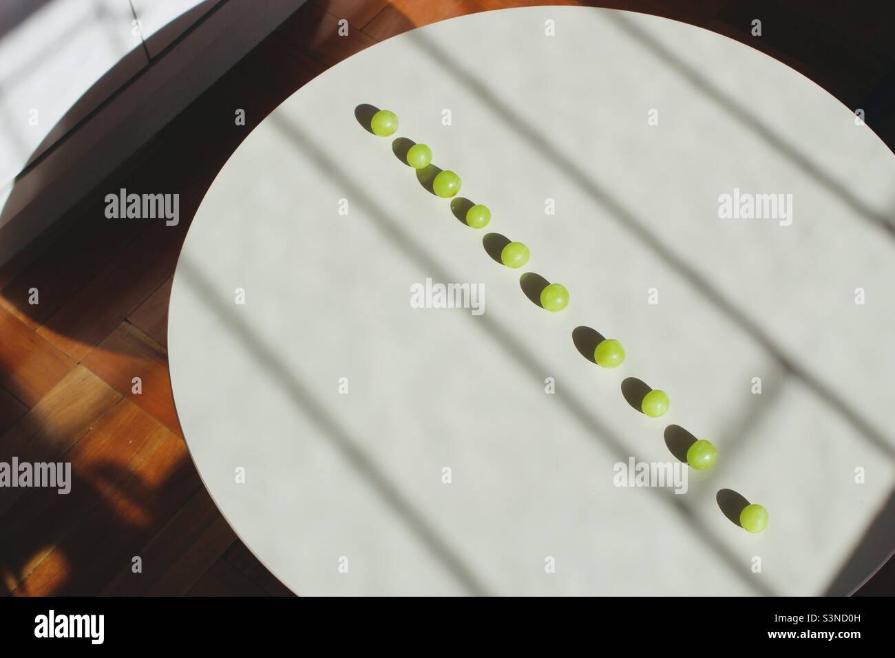 Grüne Trauben in einer Reihe auf dem Tisch. Perfekte Linien - Smartphone-aufgenommenes Stockfoto