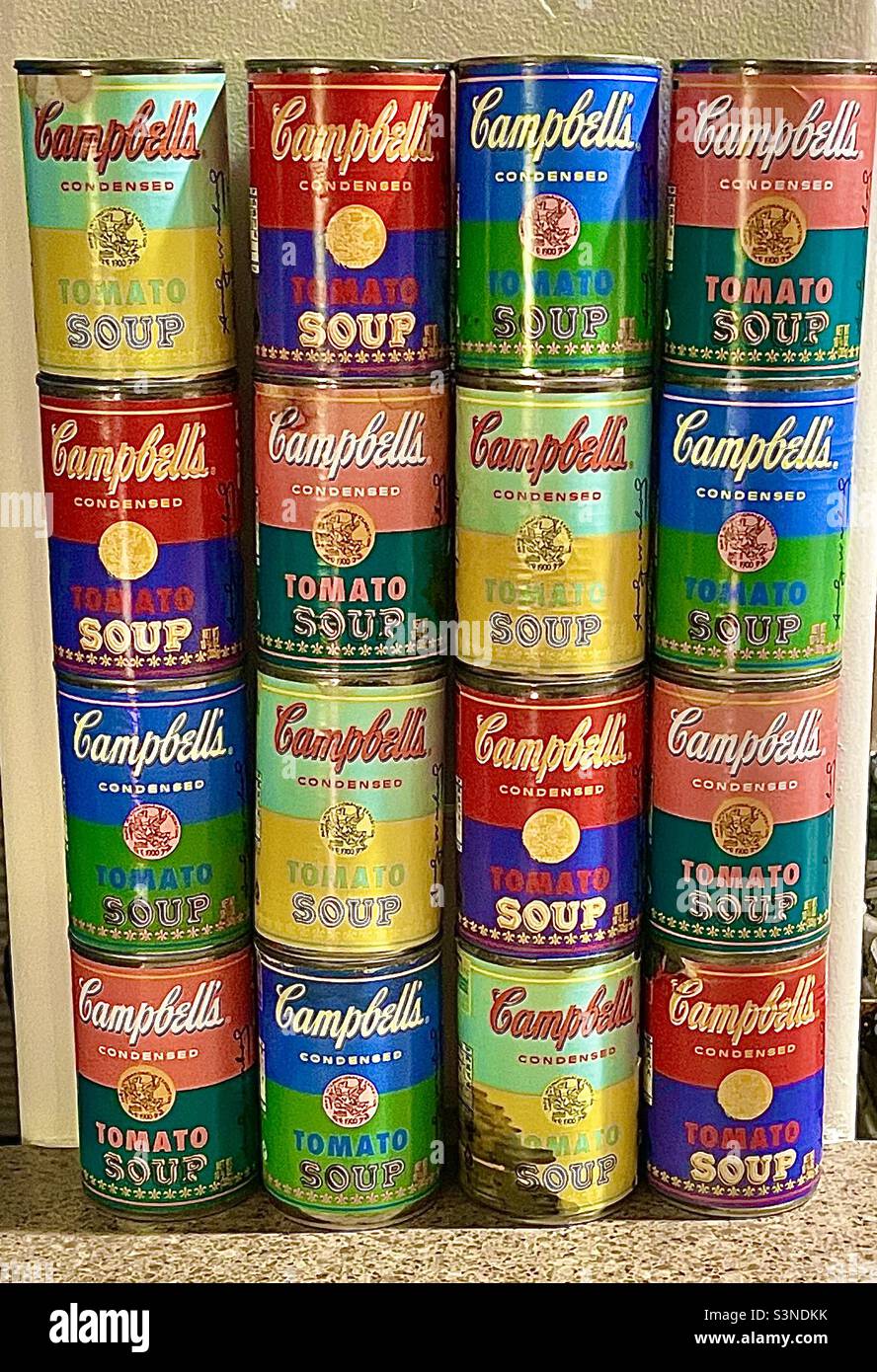 Eine etwas abgenutzte Sammlung/Ausstellung von einem Dutzend Campbell-Suppendosen im Warhol-Stil, ungeöffnet und mit Suppe gefüllt. Die Dosen wurden speziell als Warhol-Erinnerungsstücke aus der Popkunst gemustert und verkauft Stockfoto