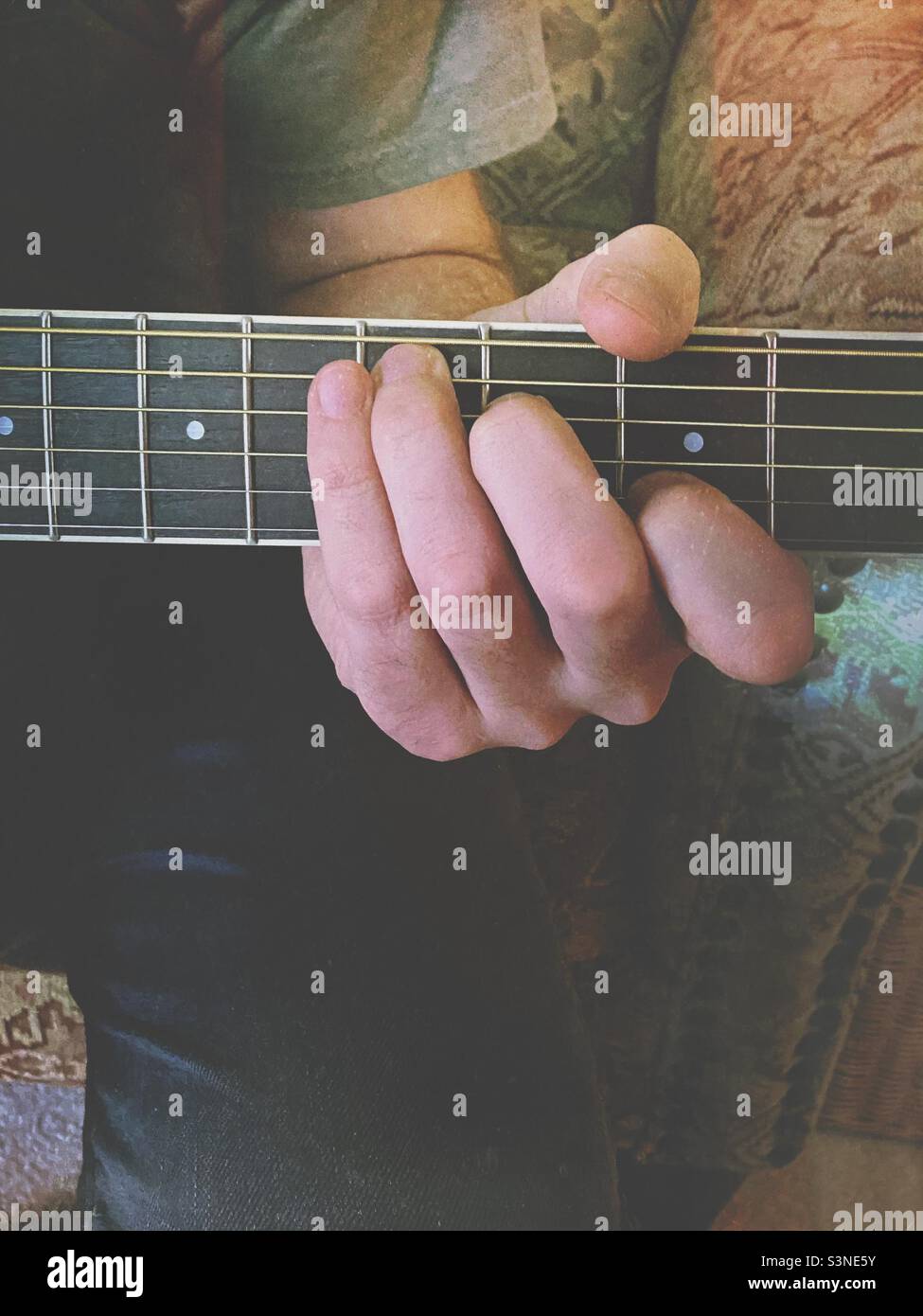 Eine Männerhand, die einen Akkord auf dem Griffbrett einer Gitarre Spielte, Wurde Mit Einem Mextures-Filter verwendet. Stockfoto
