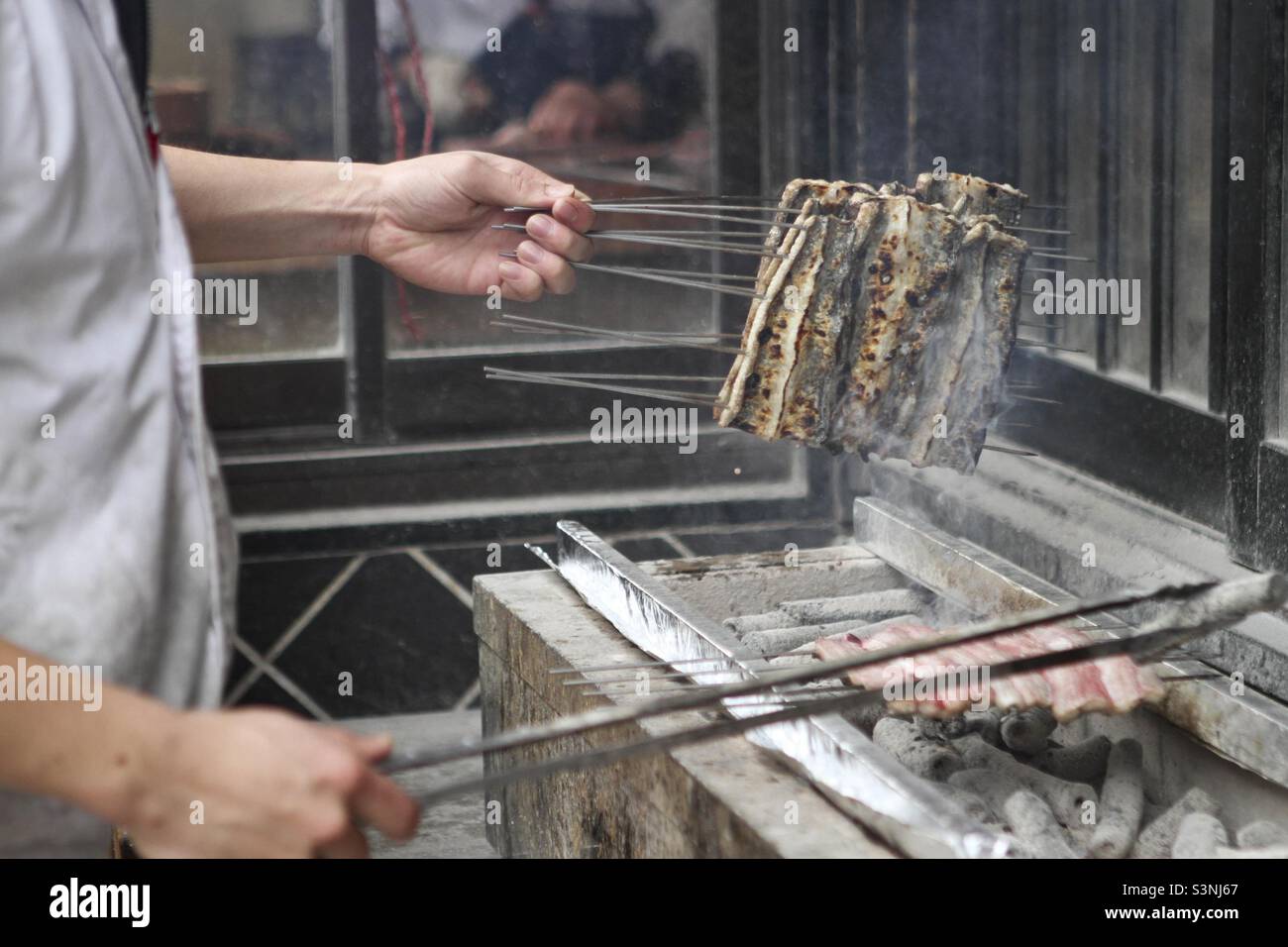 Mann, der Fleisch gegrillt hat, Straßenessen in Hanoi, Vietnam Stockfoto