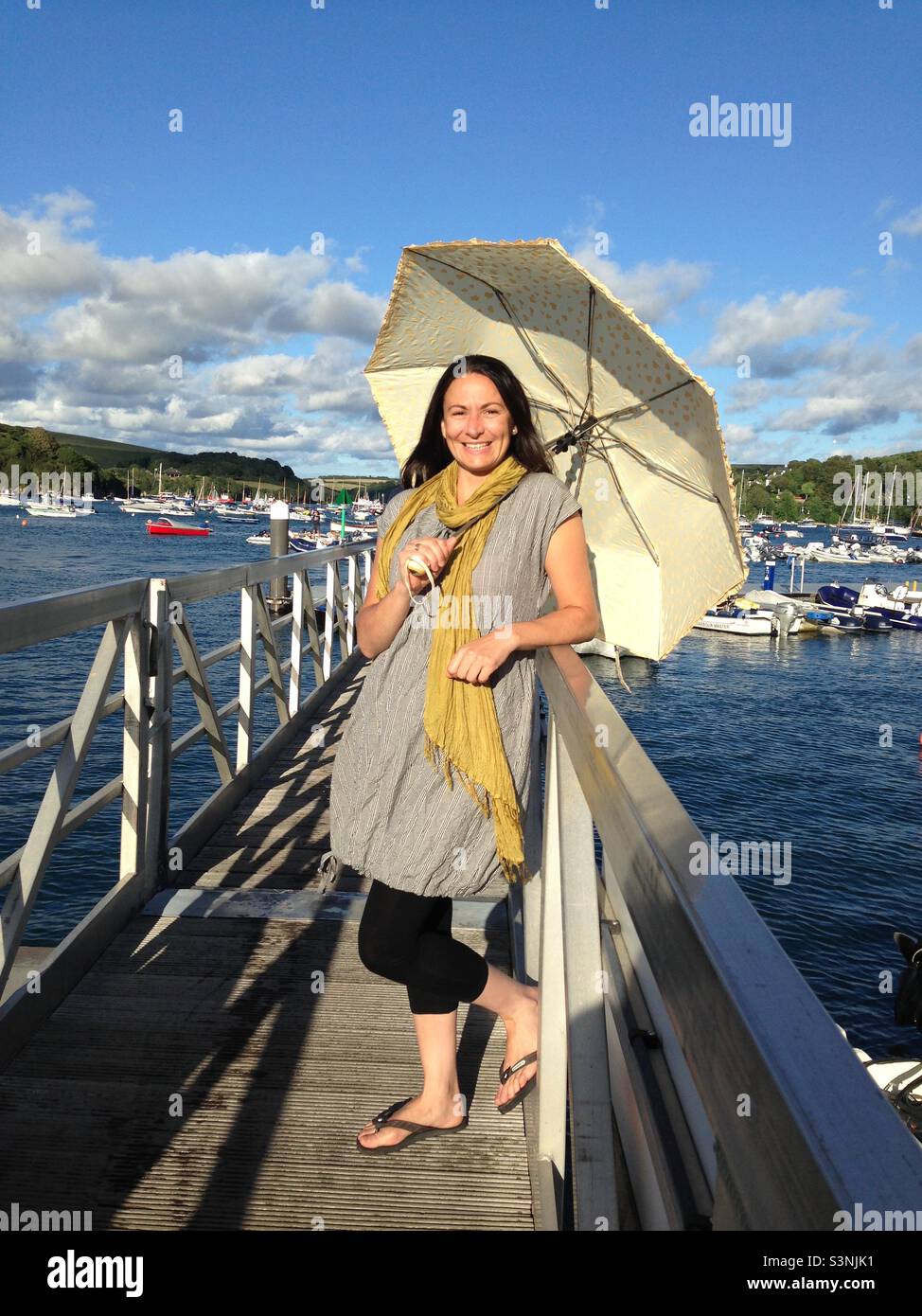 Europäische Dame hält einen Sonnenschirm auf einem Pier in Salcombe, South Devon. Stockfoto