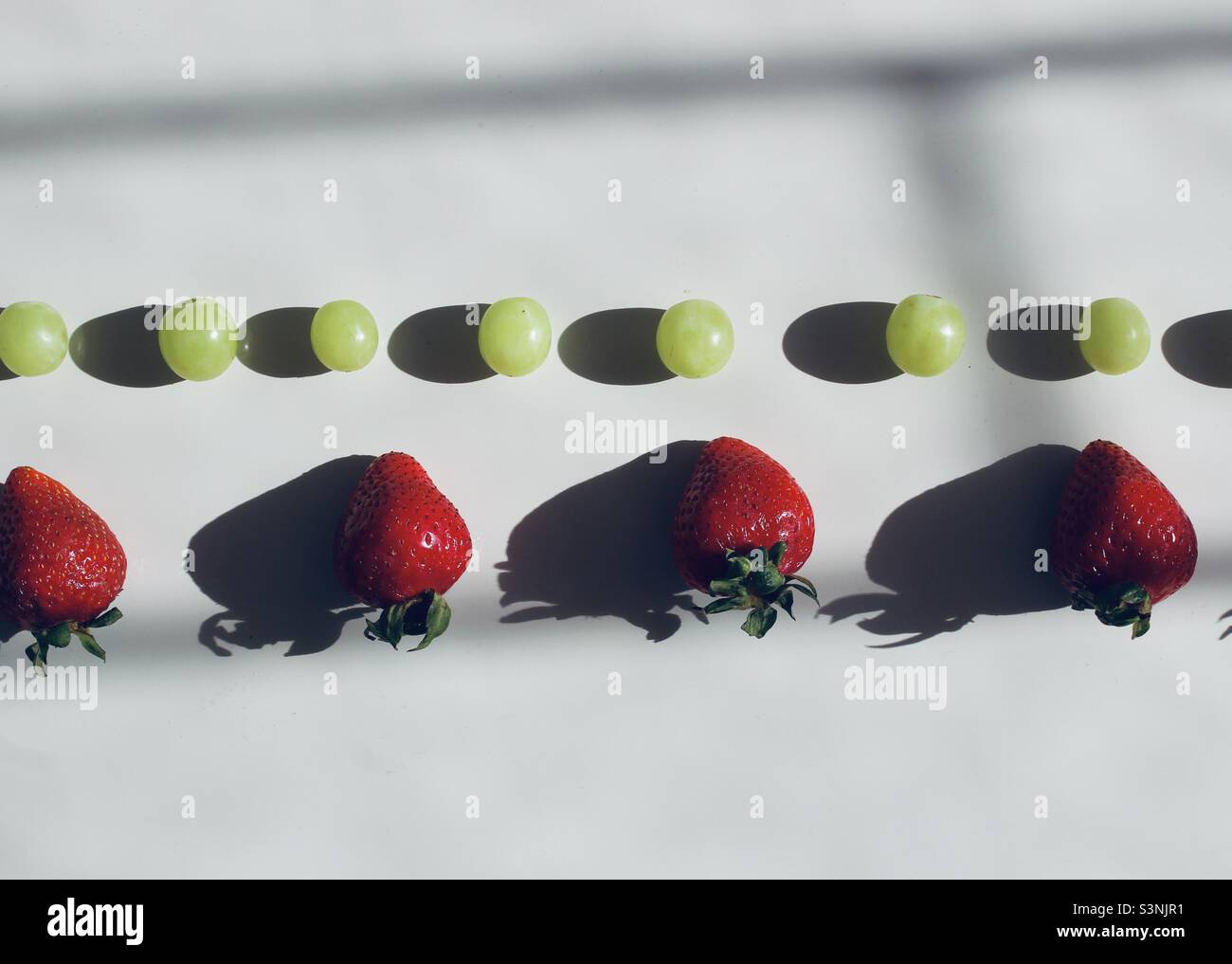 Reihen von grünen Trauben und Erdbeeren - Smartphone-aufgenommenes Stockfoto