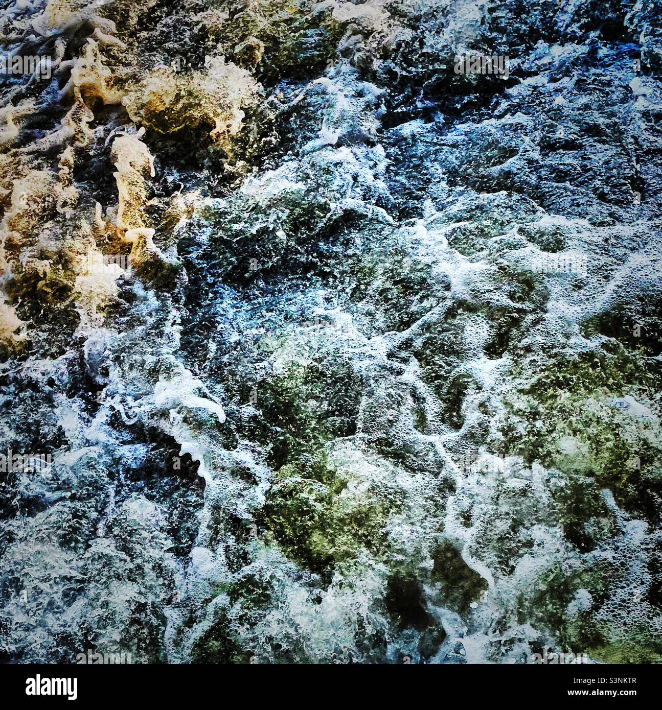 ‘Splash!’ Eine ganz nahe Sicht auf das sprudelnde Wasser, während es vom Fluss oben abstürzt. Sonnenlicht fängt ihn ein und verleiht ihm einen farbenfrohen Farbton Stockfoto