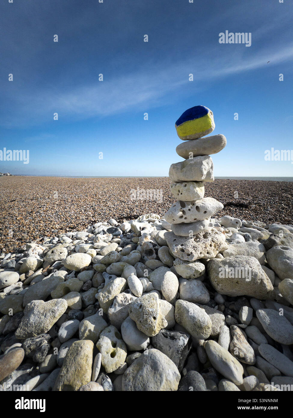 Worthing. Großbritannien: Am worthing-Strand vor den Künstlerstudios am Strand ist Am 27. Und 02-2022 Ein „Friedenspapel“ aus weißen Steinen zu sehen, der mit einem mit ukrainischer Flagge bemalten Stein gekrönt ist Stockfoto