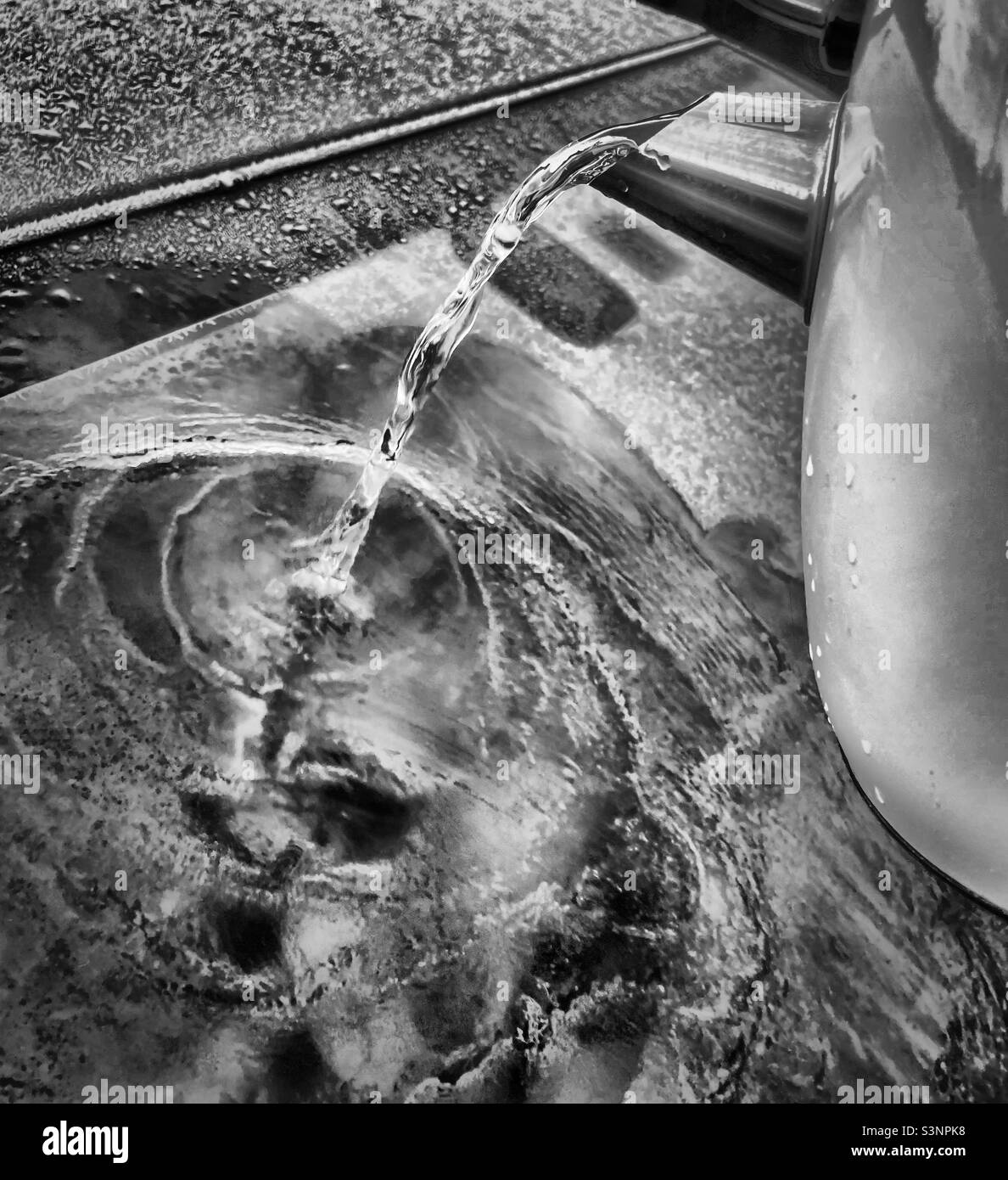 ‘Ein Wasserkocher ist oft benutzt’ kochendes Wasser aus einem Wasserkocher trifft die gefrorene Windschutzscheibe eines Autos, als ein Autofahrer versucht, es aufzutauen Stockfoto