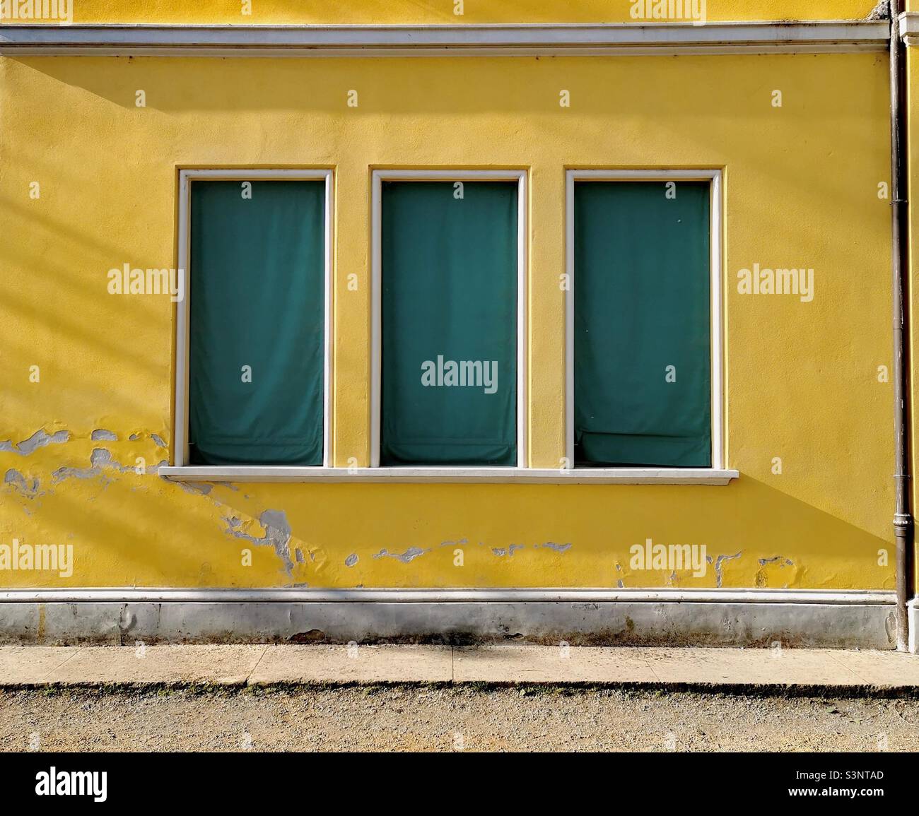 Gelbe Fassade des Schulgebäudes mit grünen Rollläden aus Leinwand Stockfoto