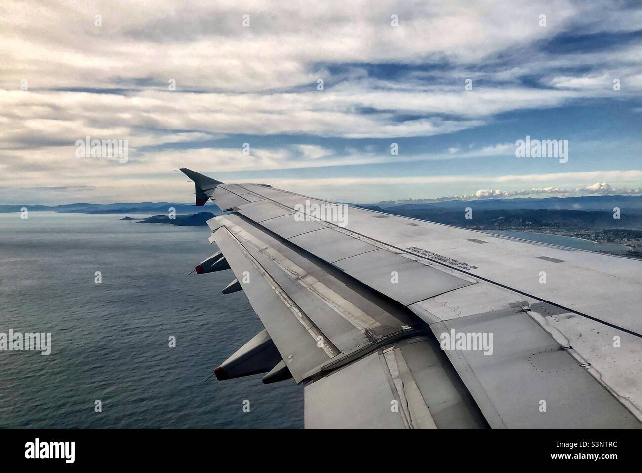 Flügel des Flugzeugs im Flug über die Küste - Smartphone-aufgenommenes Stockfoto