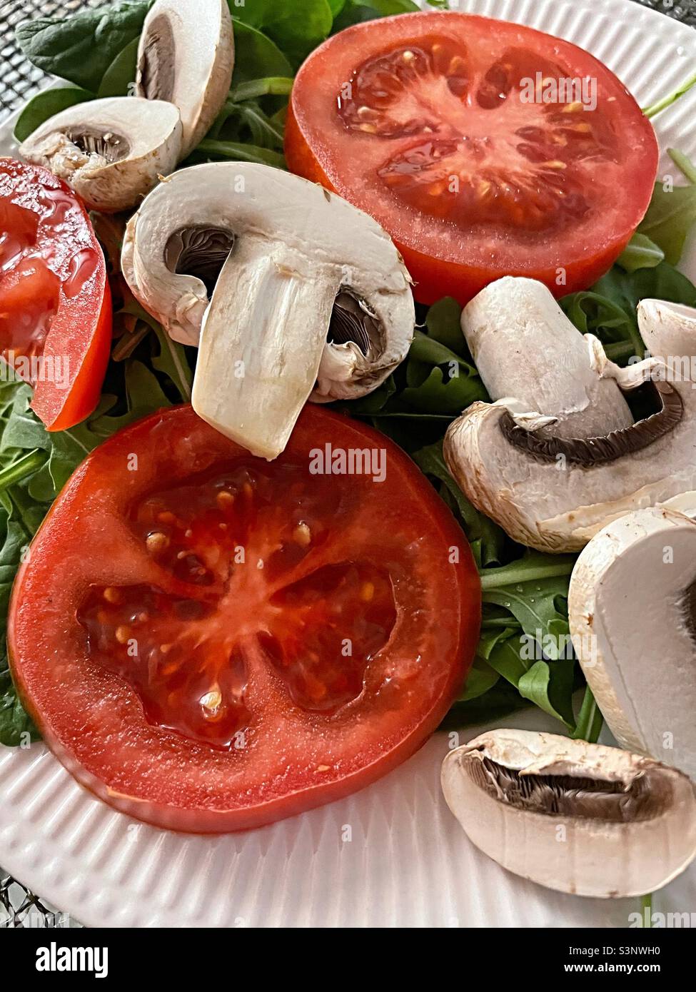 Nahaufnahme eines frischen grünen Salats mit geschnittenen Pilzen und weingereiften Tomaten, 2022, USA Stockfoto