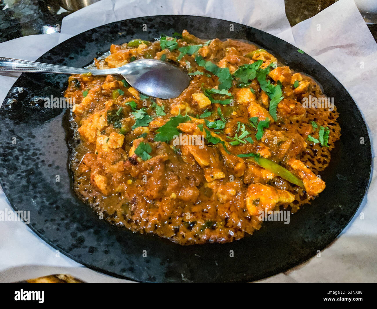 Chicken Balti wird auf gusseiserner Pfanne im indischen Restaurant serviert Stockfoto