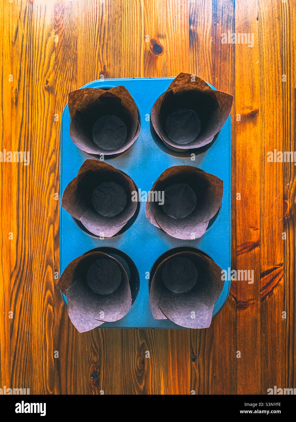 6-Loch-Muffin-Dose, gefüllt mit braunen Muffin-Koffern aus Papier - Smartphone-aufgenommenes Stockfoto