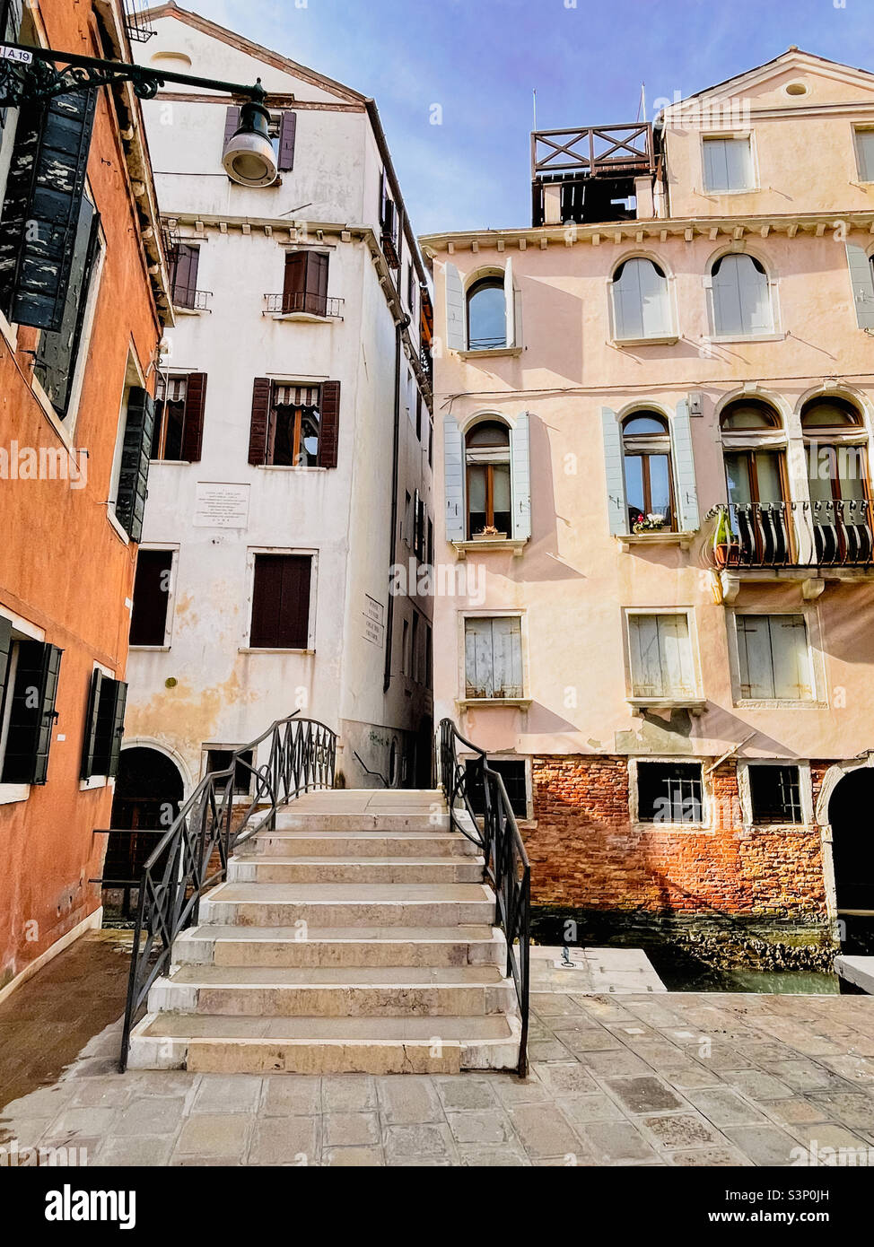 Wohngebäude mit einer kleinen Fußgängerbrücke, die an einem sonnigen Februartag über einen kleinen Kanal in Venedig, Italien, führt. Stockfoto