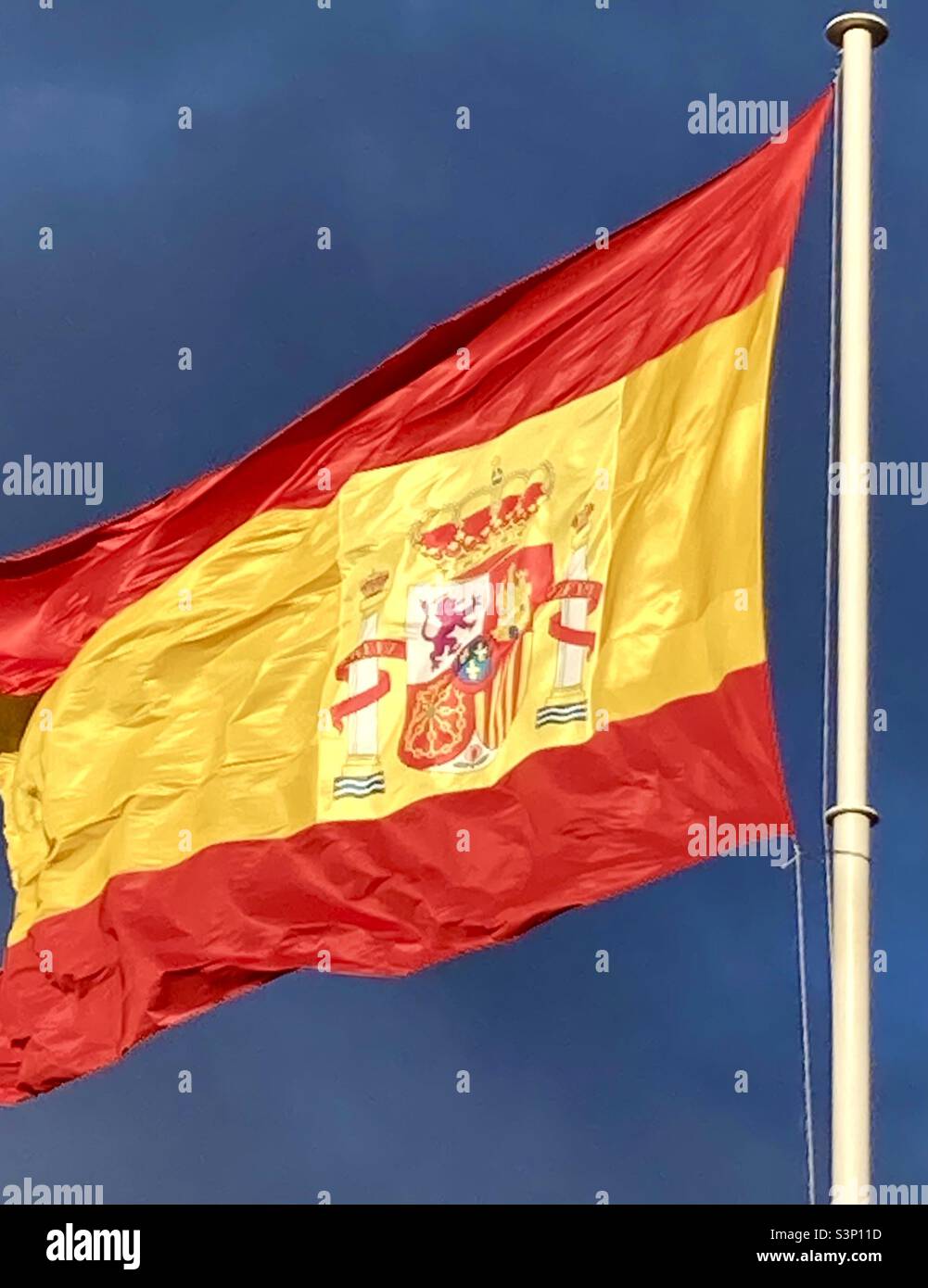 Verlängerte spanische Flagge fliegt bei starkem Wind an einem heißen Sommertag vor einem dunkelblauen Himmel Madrid Spanien Stockfoto