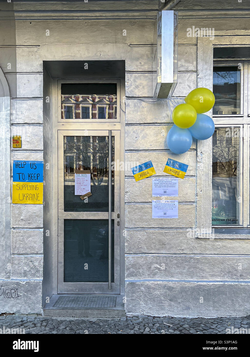 Bitten Sie um Hilfe. Gelbes und blaues Poster auf dem Gebäude während der russischen Militärinvasion in der Ukraine - Mitte, Berlin, Deutschland Stockfoto