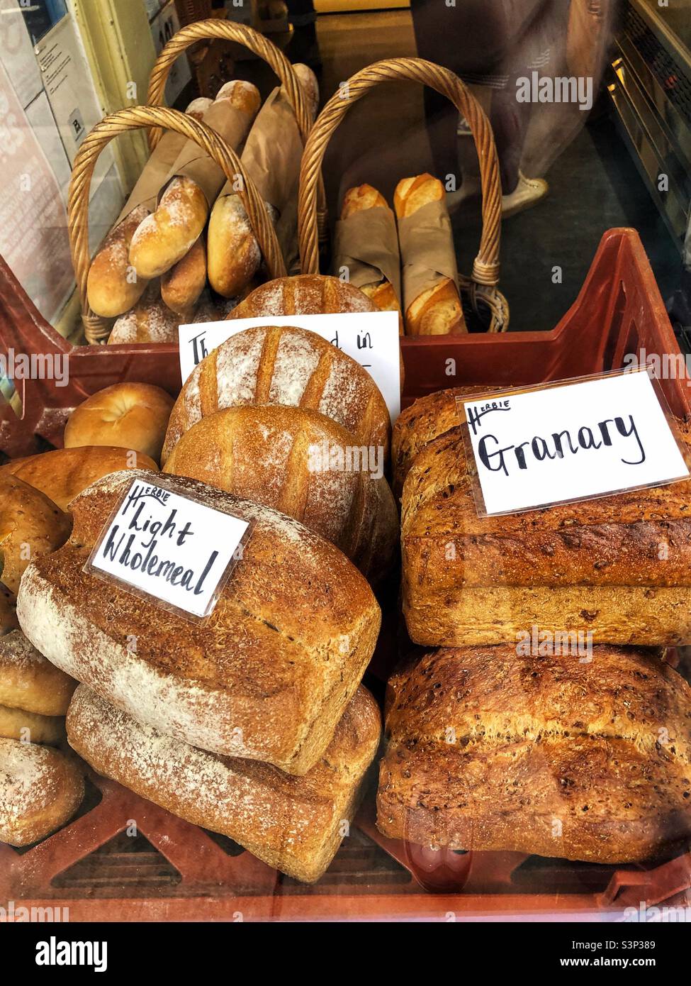 Frische Aritisan-Brote in einem Fenster mit Delikatessen und Wurstwaren Stockfoto
