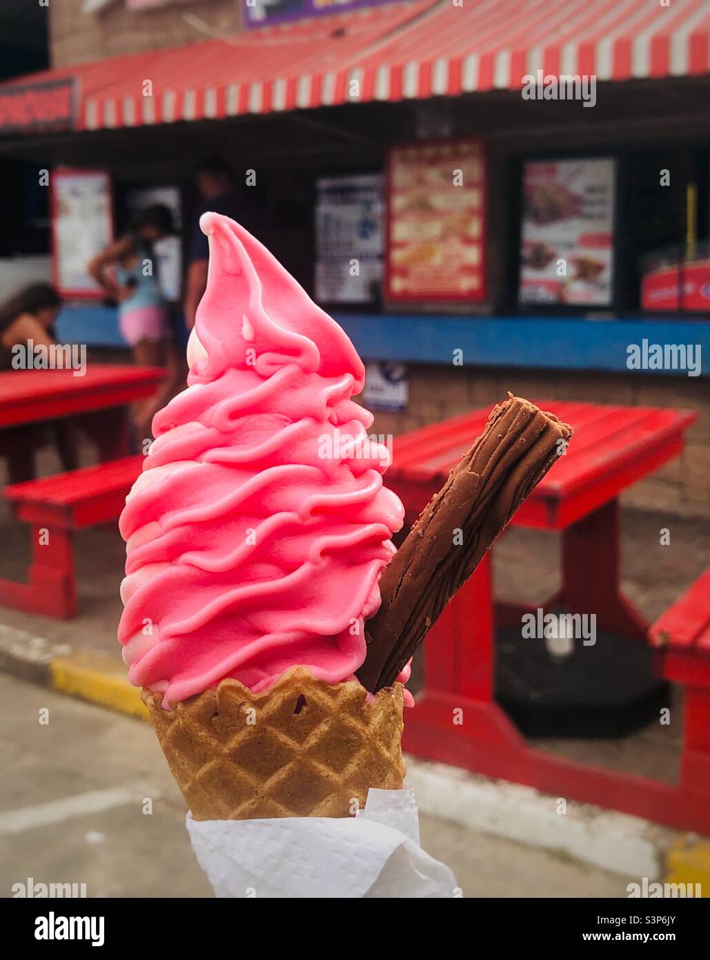 Eis mit Erdbeergeschmack in einem Zuckerkonus mit einer Cholesterinflocke Stockfoto