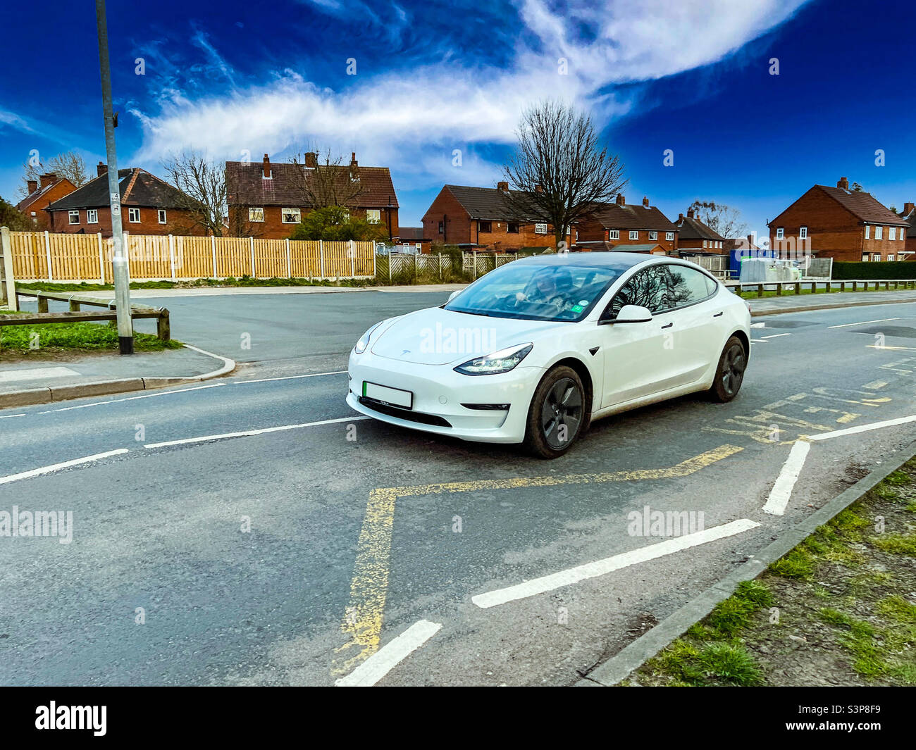 Weißes Tesla Modell 3 Elektrofahrzeug im urbanen England - Smartphone-aufgenommenes Stockfoto