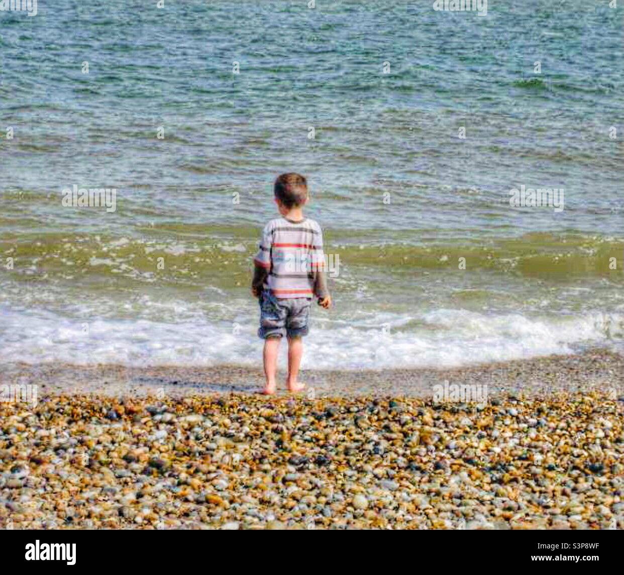 Kleiner Junge Steinewerfen ins Meer Stockfoto