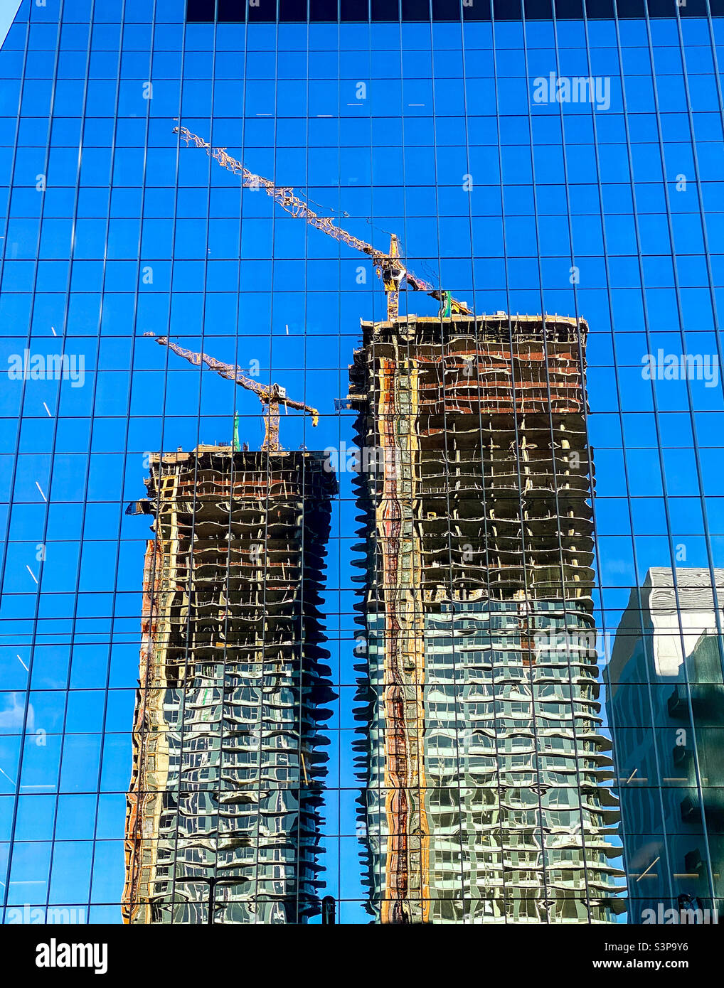 Der Neubau von Wohntürmen spiegelte sich während des Baubooms in Seattle, Washington, in einem weiteren neu fertiggestellten Gebäude wider - Smartphone-aufgenommenes Stockfoto