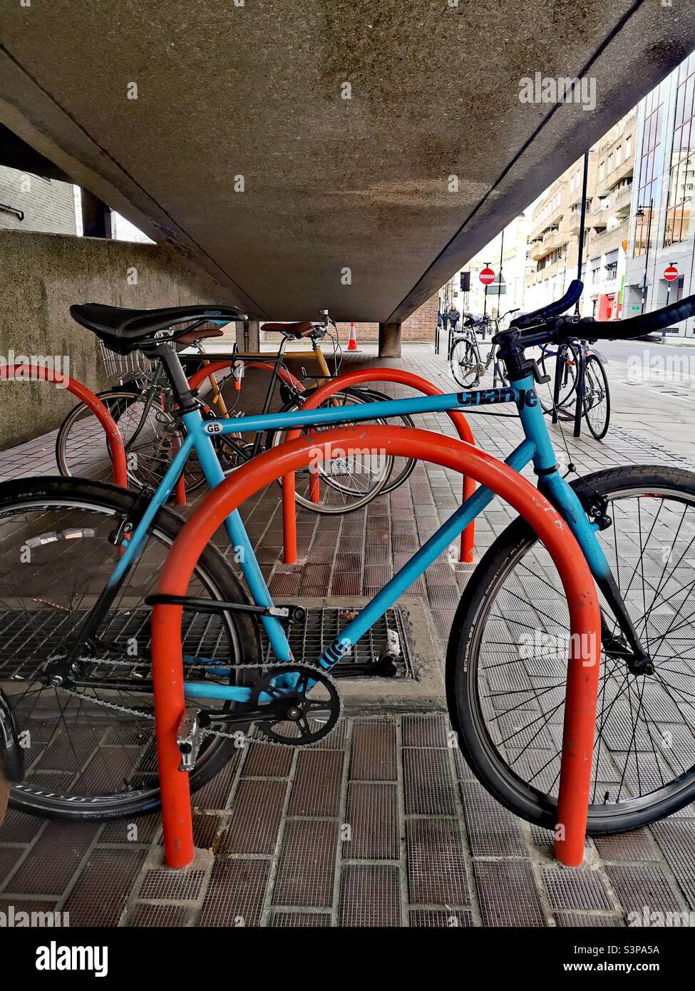 Blaues Fahrrad an orangefarbenem Fahrradträger verriegelt Stockfoto