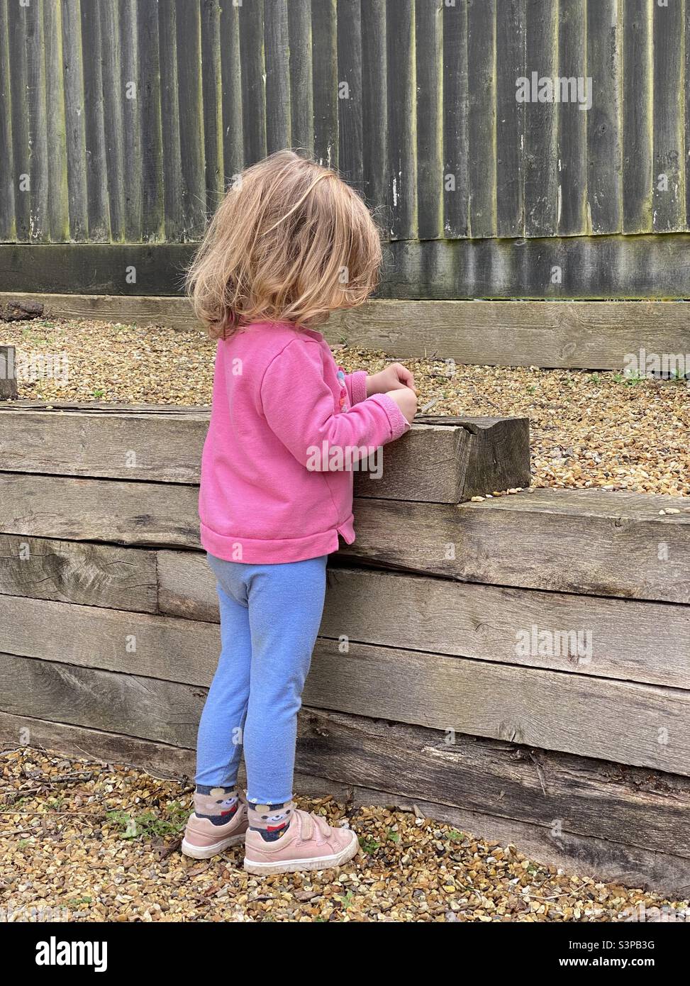Kleines Kind, das an der Gartenmauer spielt Stockfoto