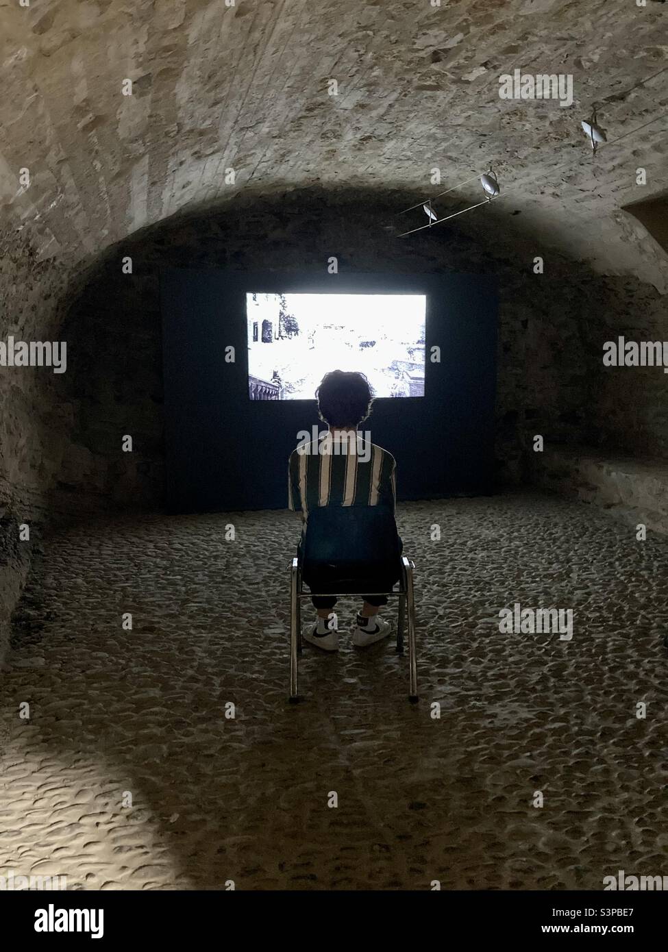 Mann, der im Castello dei Doria einen Film über die Geschichte des mittelalterlichen Dorfes Dolceacqua in Italien ansieht. Stockfoto