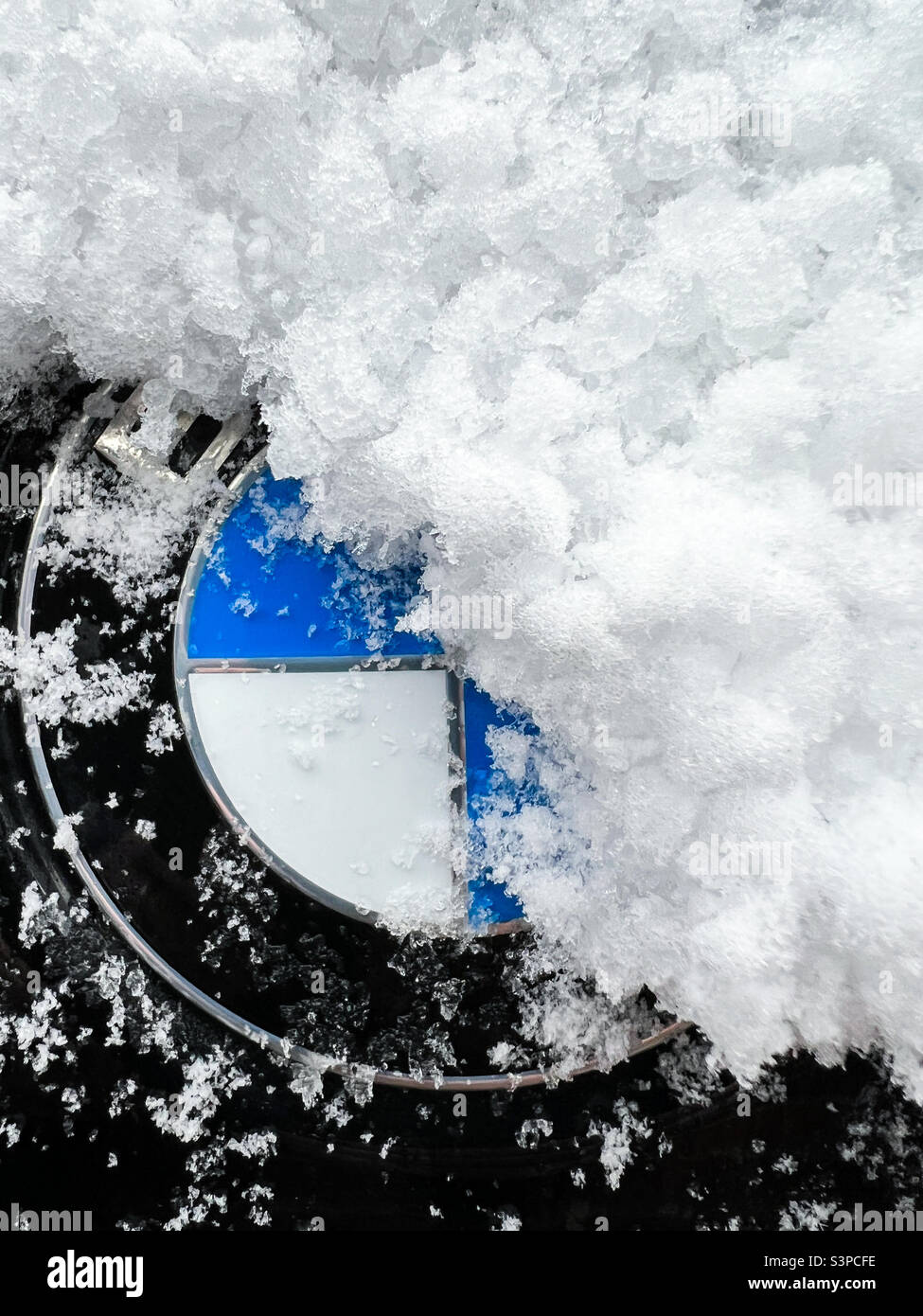 Mit Schnee bedecktes BMW-Logo-Emblem - Smartphone-aufgenommenes Stockfoto