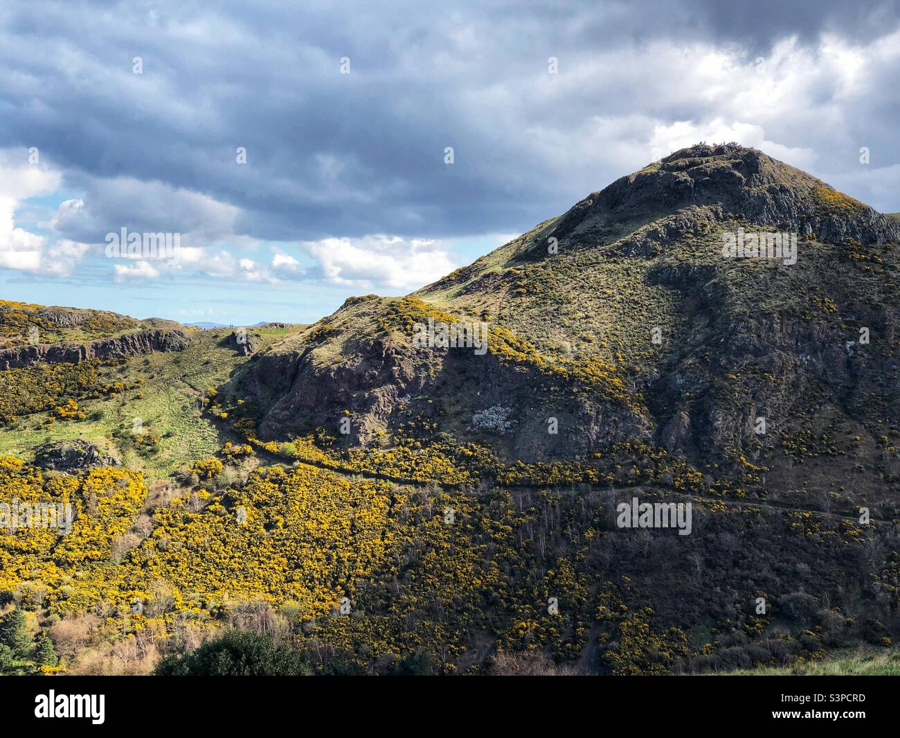 Menschen sichtbar auf dem Gipfel des Arthur’s Seat von der Nachmittagssonne beleuchtet, Holyrood Park, Edinburgh, Schottland - Smartphone-aufgenommenes Stockfoto
