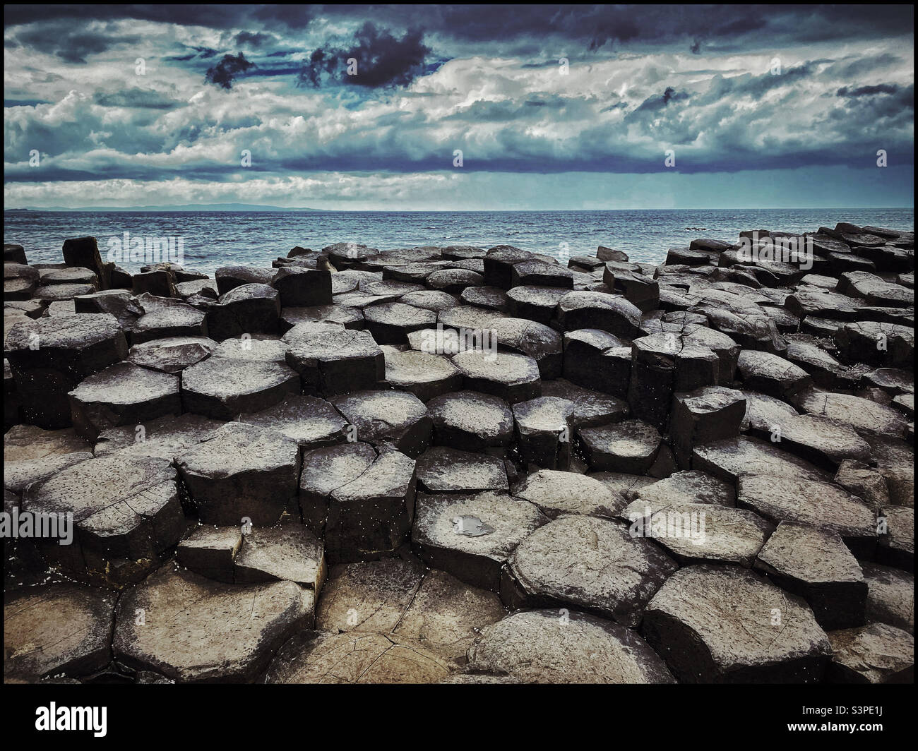Ein launisches Landschaft-/Seebild eines Sturms über Giant’s Causeway in Nordirland, Großbritannien. Dieser interessante geologische Standort wurde vor etwa 66 Millionen Jahren durch Vulkanausbrüche geschaffen Stockfoto