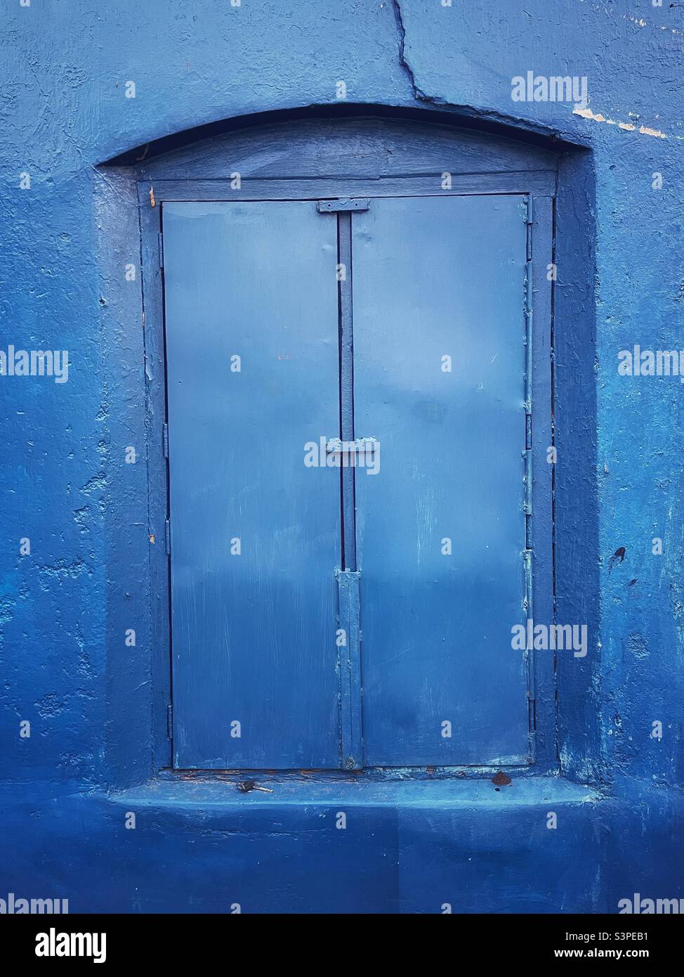 Ein geschlossenes Fenster auf blauem Wandhintergrund Stockfoto