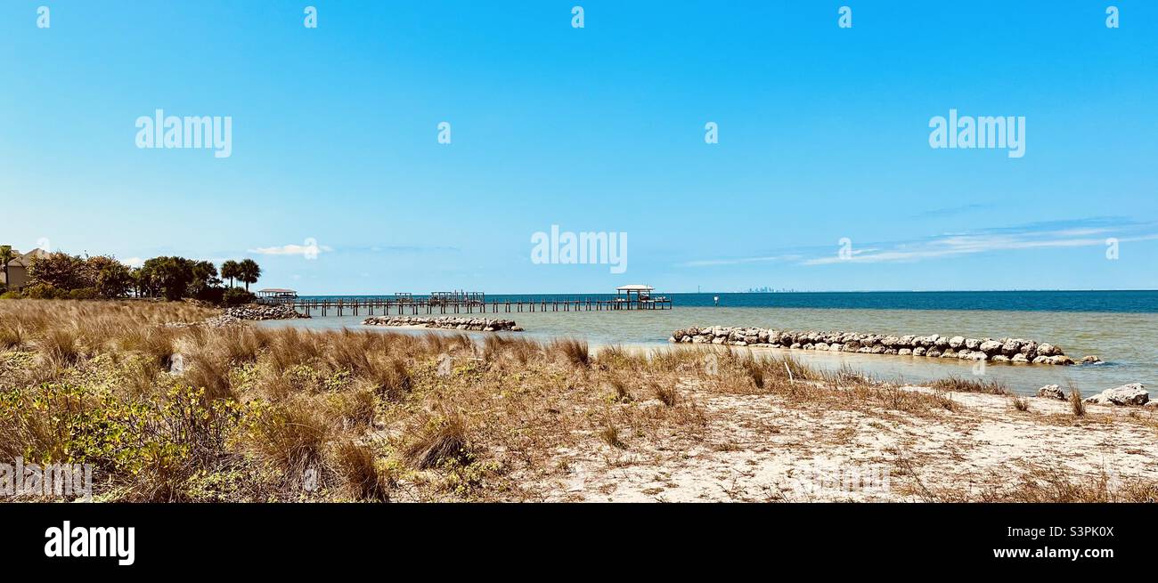 Strand in Florida mit naheliegendem Pier und Stadtumriss in der Ferne. Filter „lebhaft warm“ angewendet. Stockfoto
