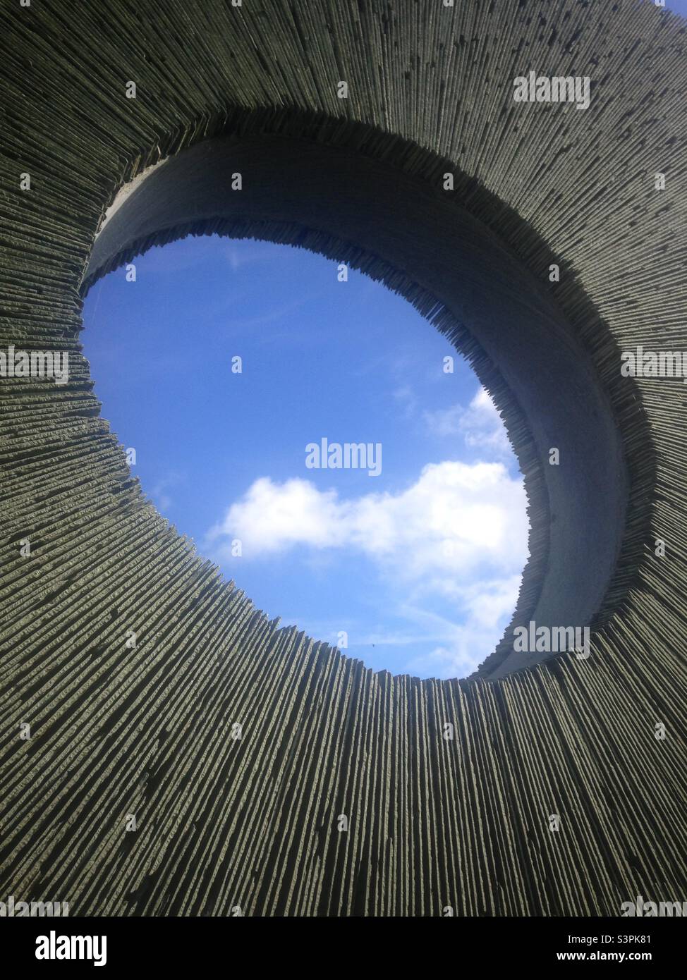 Blick auf blauen Himmel und flauschige Wolken durch eine Steinskulptur. Stockfoto