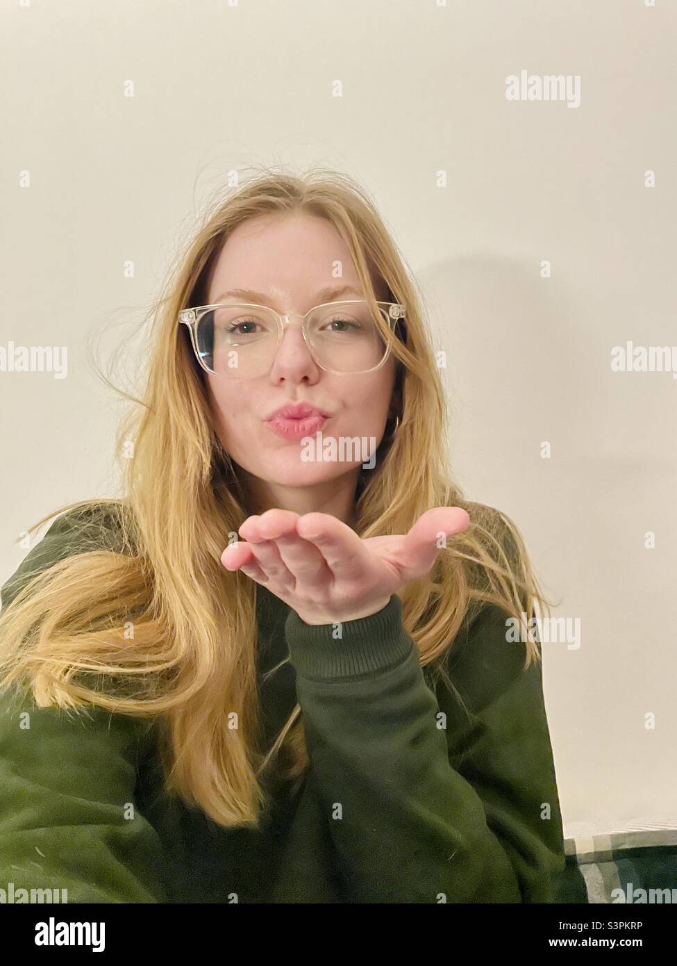 Junge Frau weht ein Kuss - Smartphone-aufgenommenes Stockfoto