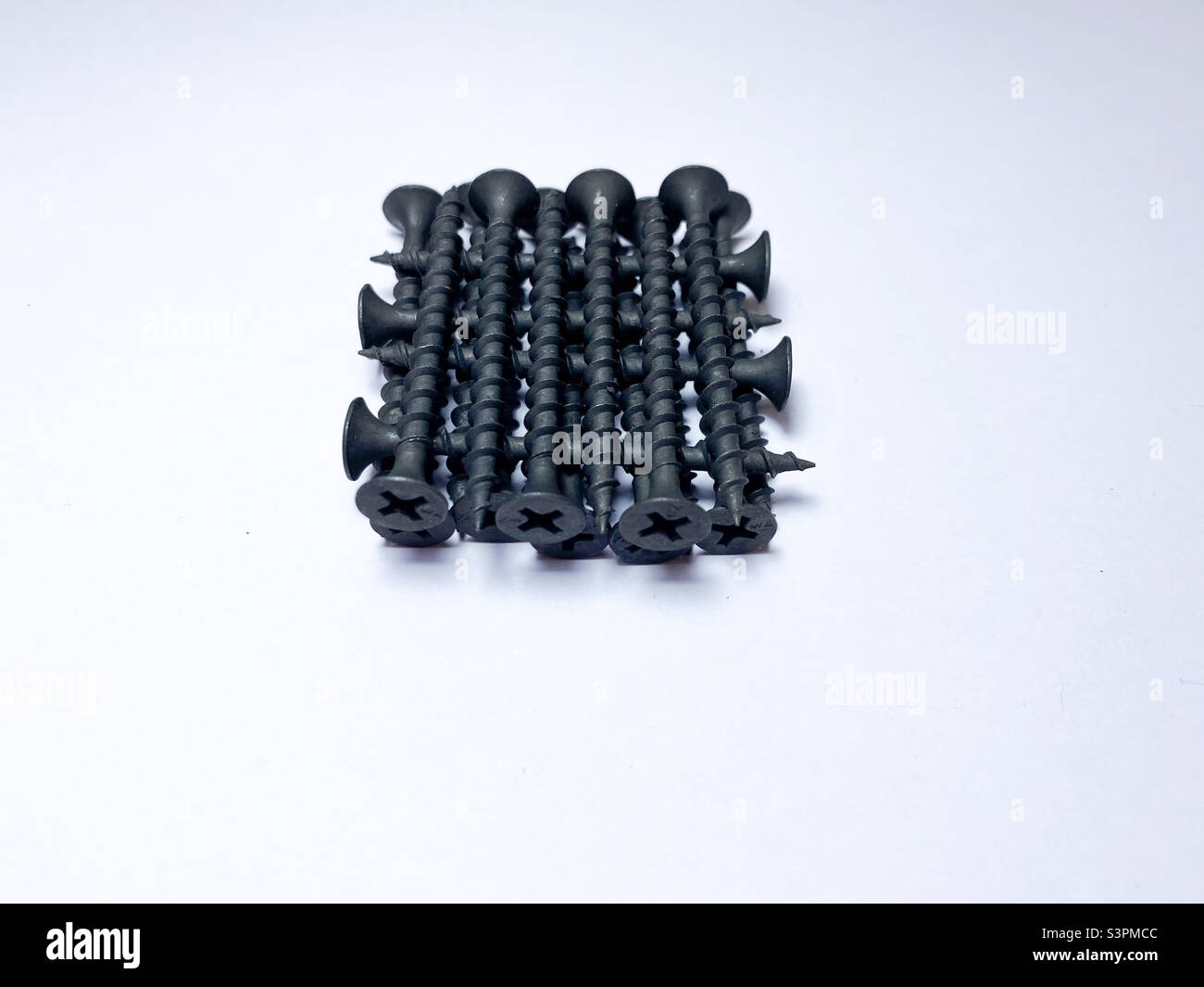 Selbstschneidende Schrauben auf schwarzem Metall auf weißem, isoliertem Hintergrund Stockfoto