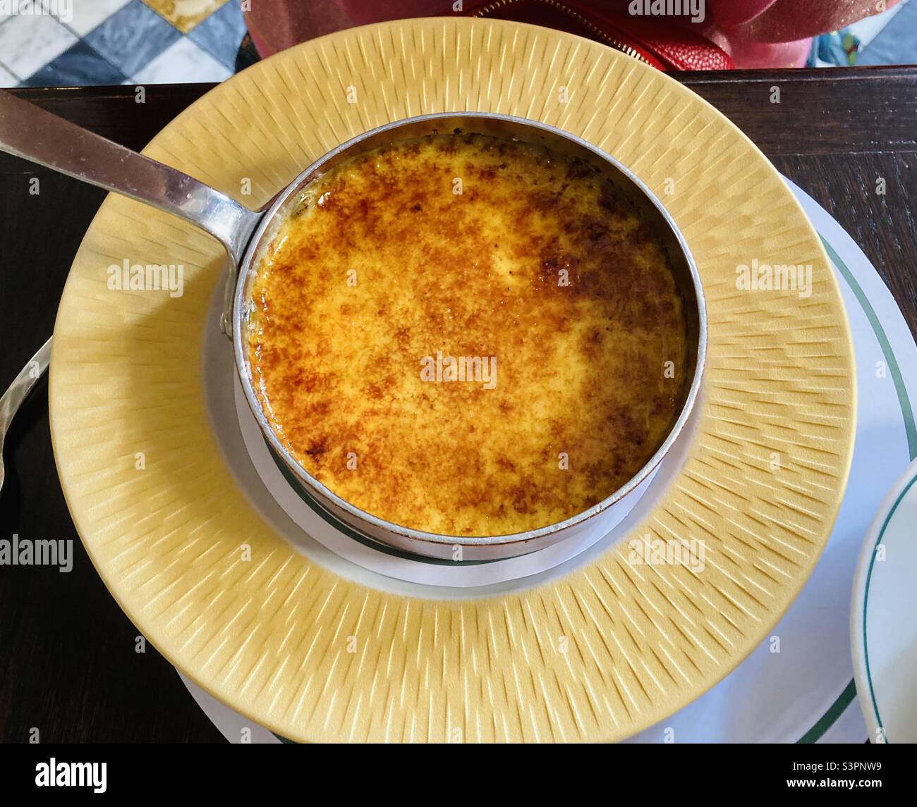 Creme brûlée von oben auf einem gelben Teller im Restaurant Ivy - Smartphone-aufgenommenes Stockfoto