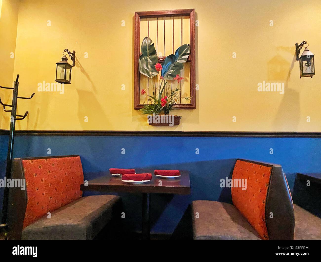 Restaurant-Tisch mit Wanddekor, Kleiderbügel und antiken Lampen. Stockfoto