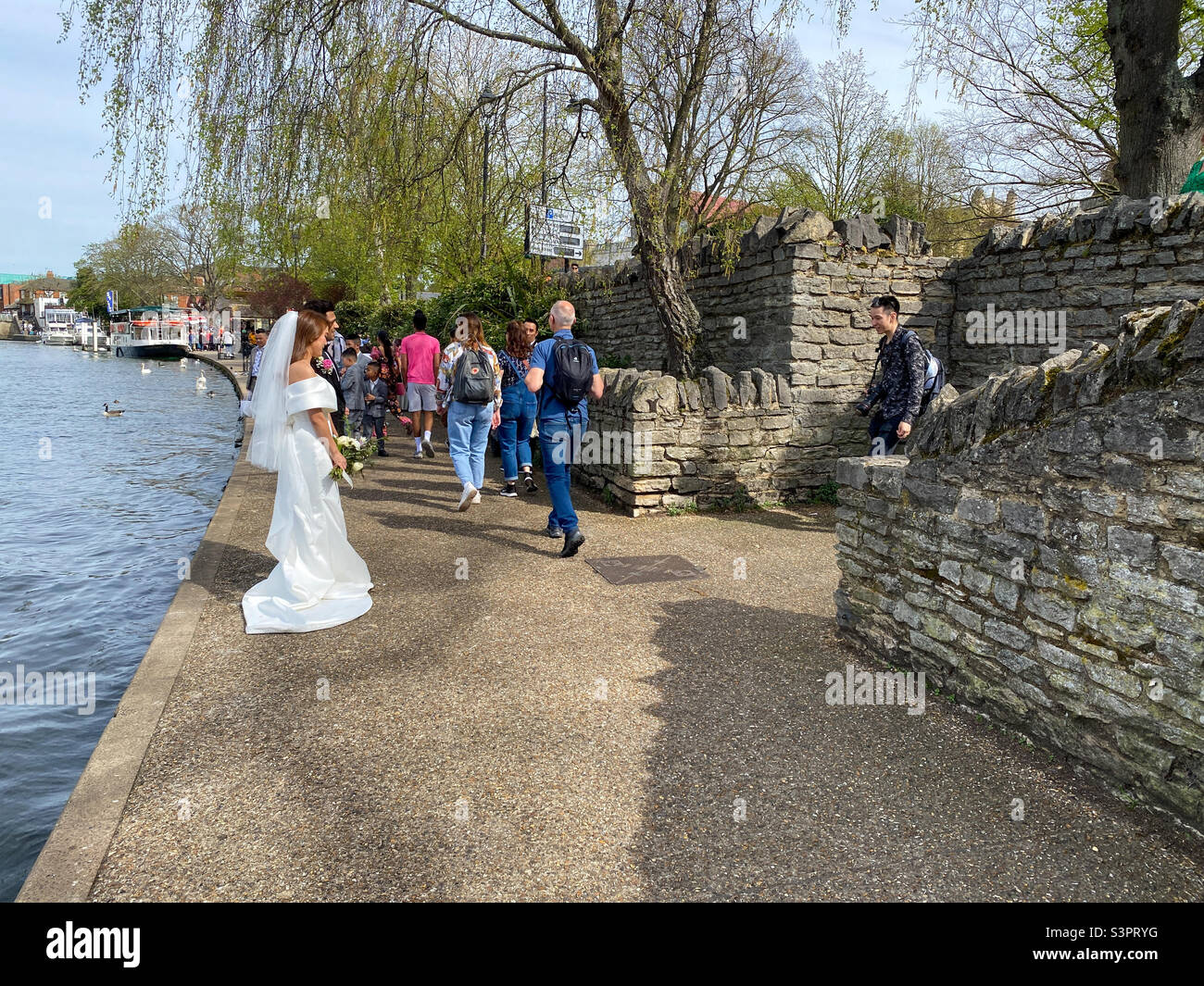 Ein frisch verheiratetes Paar und ihr Fotograf machen Hochzeitsfotos am Ufer der Themse in Windsor, Großbritannien Stockfoto