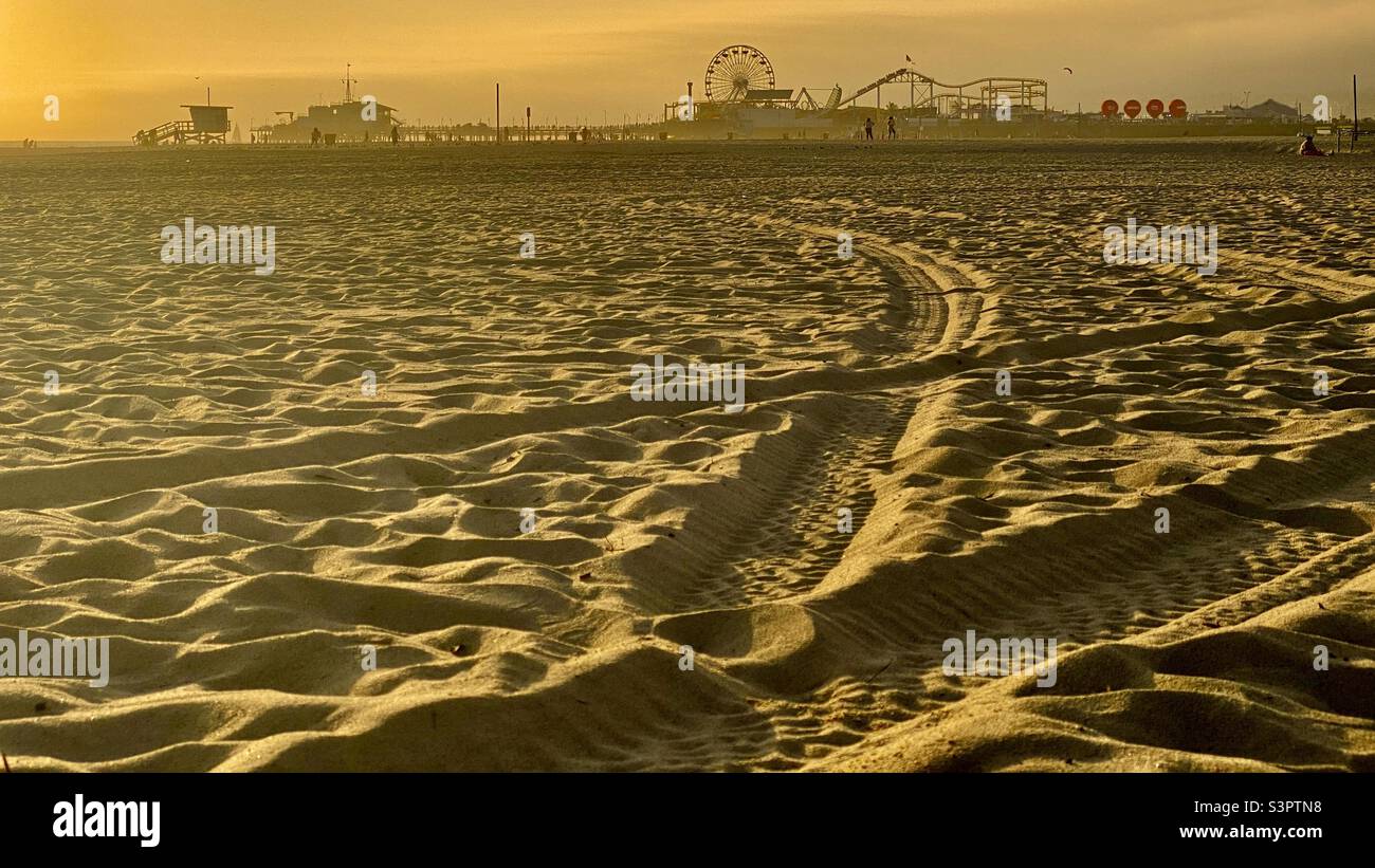 Blick über den Sand am späten Nachmittag, goldenes Licht, auf den Strand von Santa Monica mit Fokus auf silhouetted Pier in der Ferne - Smartphone-aufgenommenes Stockfoto