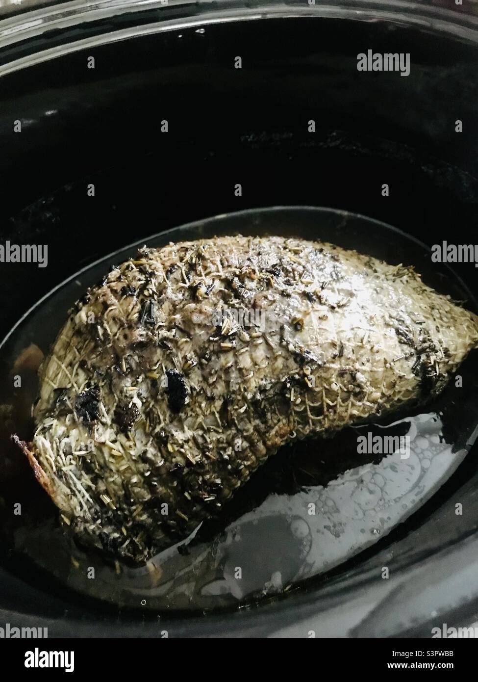 Rinderbraten im langsamen Herd - mit Olivenöl, Rosmarin und Basilikum beträufelt Stockfoto