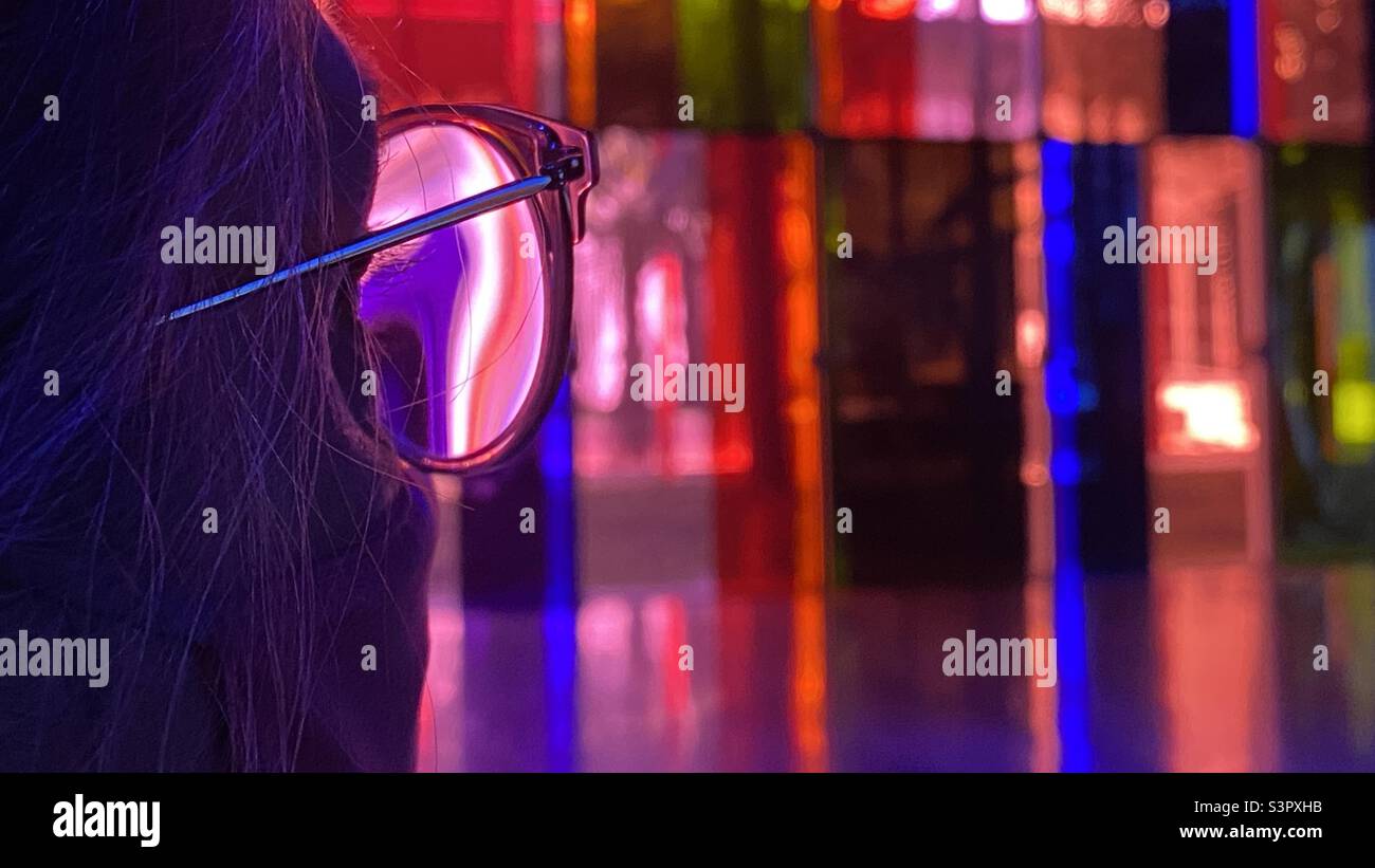 Anonyme Frau in extremer Nahaufnahme, die durch eine Brille auf farbige gelbedeckte Fenster blickt - Smartphone-aufgenommenes Stockfoto