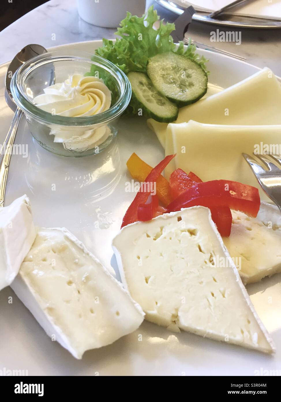 Frühstücksteller mit Käsebutter und verschiedenen Gemüsesorten - Smartphone-aufgenommenes Stockfoto
