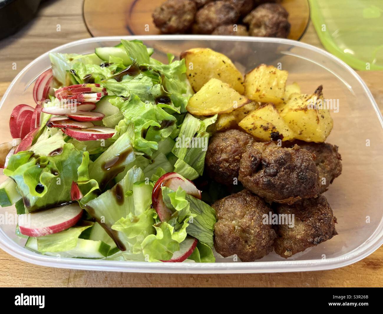 Hausgemachtes Essensset mit Fleischbällchen, Bratkartoffeln und Salat in Kunststoffbehälter für Bürokost zum Mitnehmen Stockfoto