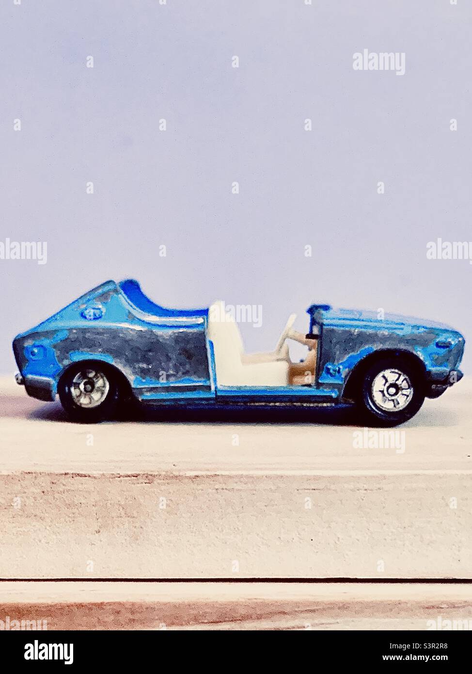 Antikes blaues Cabrio-Auto-Spielzeug im unteren Teil vor weißem Hintergrund mit Druckraum angezeigt Stockfoto