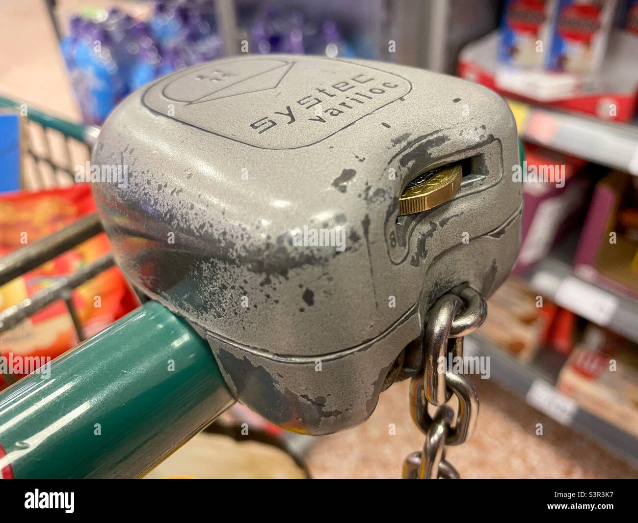 Ein Verriegelungsmechanismus auf einem Supermarktwagen, bei dem eine Pfund-Münze als Kaution eingesetzt werden muss, um den Wagen freizugeben. Stockfoto