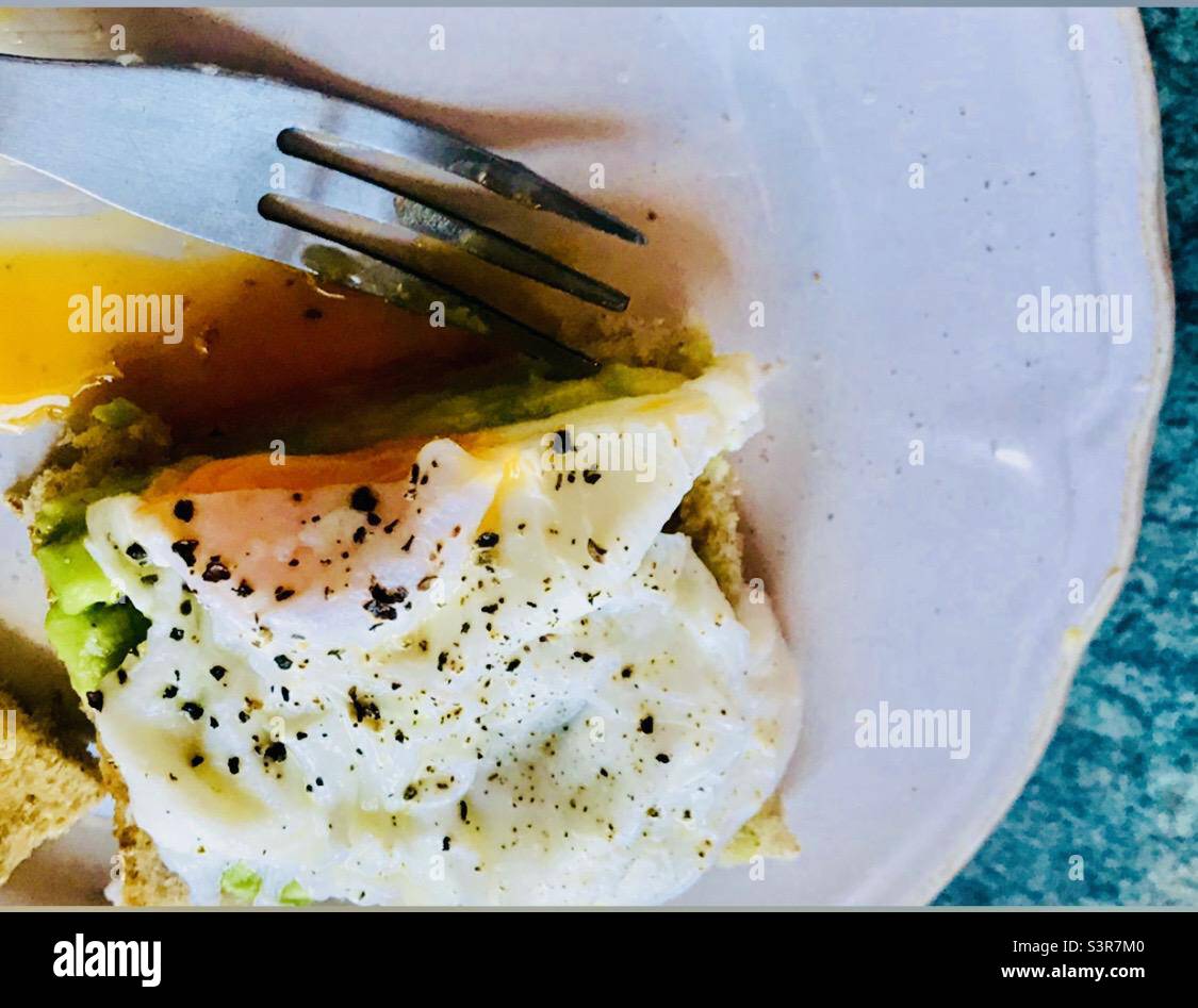 Gebratene Eier auf Toast auf einem weißen Teller mit einer Gabel öffnen Stockfoto