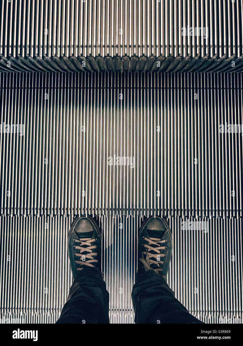 Mann auf einer beweglichen Treppenfahrtreppe, über Kopf geschossen - Smartphone-aufgenommenes Stockfoto