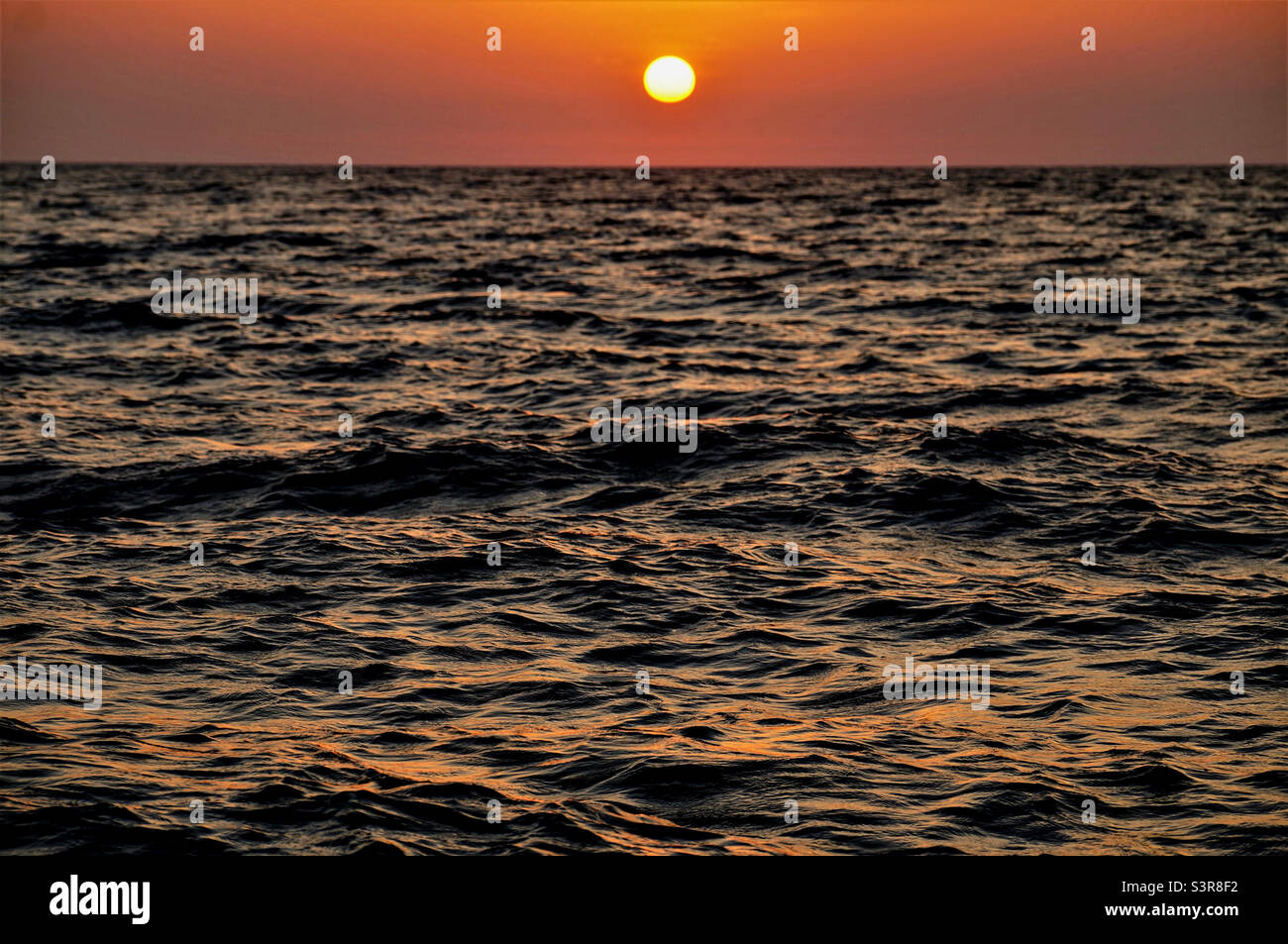 Sonnenuntergang über dem Meer mit kleinen Wellen Stockfoto