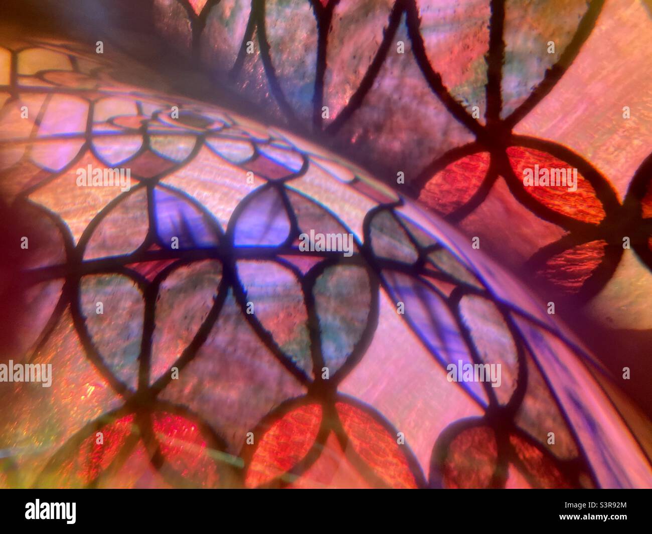 Farbenfrohes, abstraktes Muster mit Prisma vor dem Kameraobjektiv. Überlappende Bilddetails von Buntglasfenstern mit Kurven - Smartphone-aufgenommenes Stockfoto