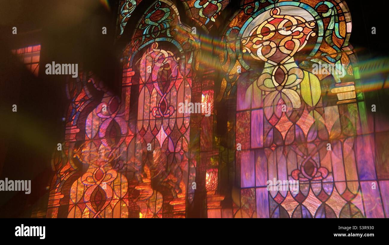 Farbenfrohes, abstraktes Muster mit Prisma vor dem Kameraobjektiv. Überlappendes Bild von Buntglasdetails mit grünen und orangefarbenen Reflexen - Smartphone-aufgenommenes Stockfoto