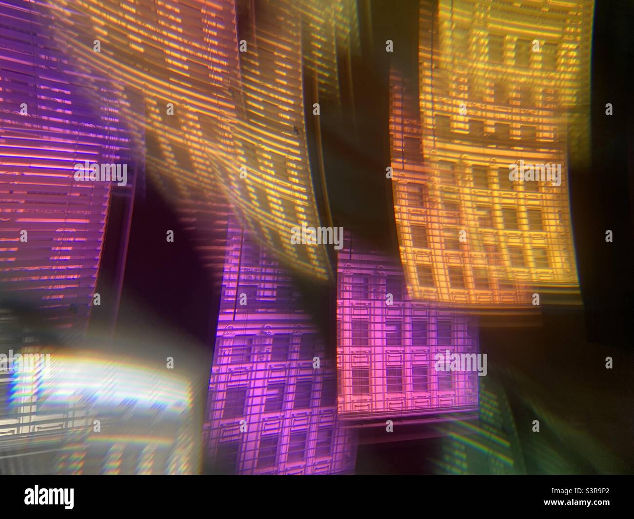 Farbenfrohes, abstraktes Muster mit Prisma vor dem Kameraobjektiv. Verzerrte Fassade eines historischen Gebäudes, das durch Jalousien als wiederholtes Bild angesehen wird - Smartphone-aufgenommenes Stockfoto