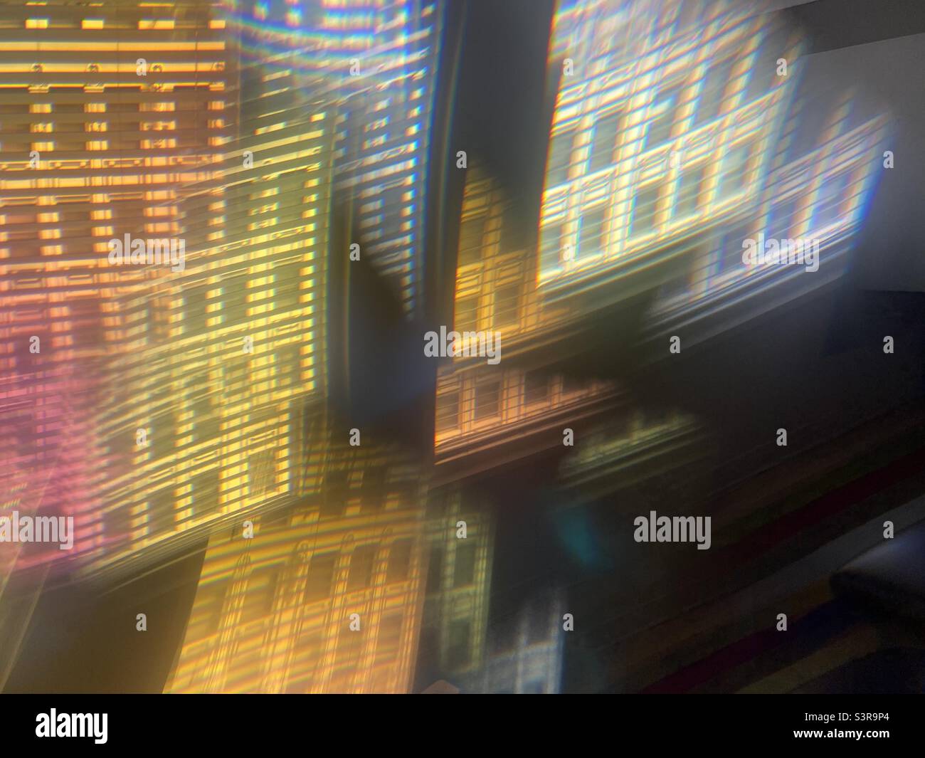 Farbenfrohes, abstraktes Muster mit Prisma vor dem Kameraobjektiv. Die Fassade eines historischen Gebäudes wird als wiederholtes Bild durch das Fenster mit Jalousien gesehen - Smartphone-aufgenommenes Stockfoto
